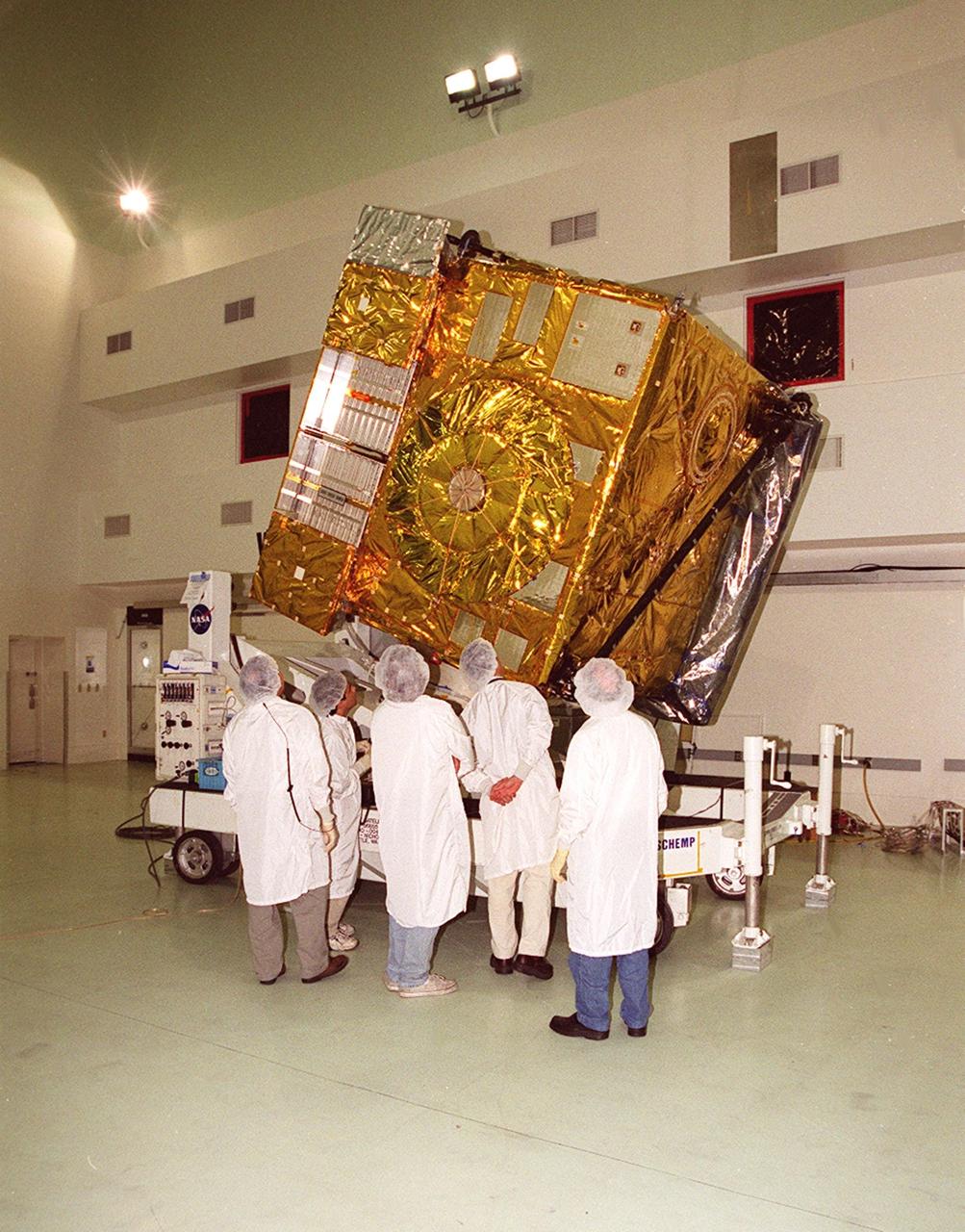 At Astrotech, Titusville, Fla., workers look over the GOES-M satellite after removal of its protective cover. The GOES-M provides weather imagery and quantitative sounding data used to support weather forecasting, severe storm tracking and meteorological research. The satellite will undergo testing at Astrotech before its scheduled launch July 12 on an Atlas-IIA booster, Centaur upper stage from Cape Canaveral Air Force Station