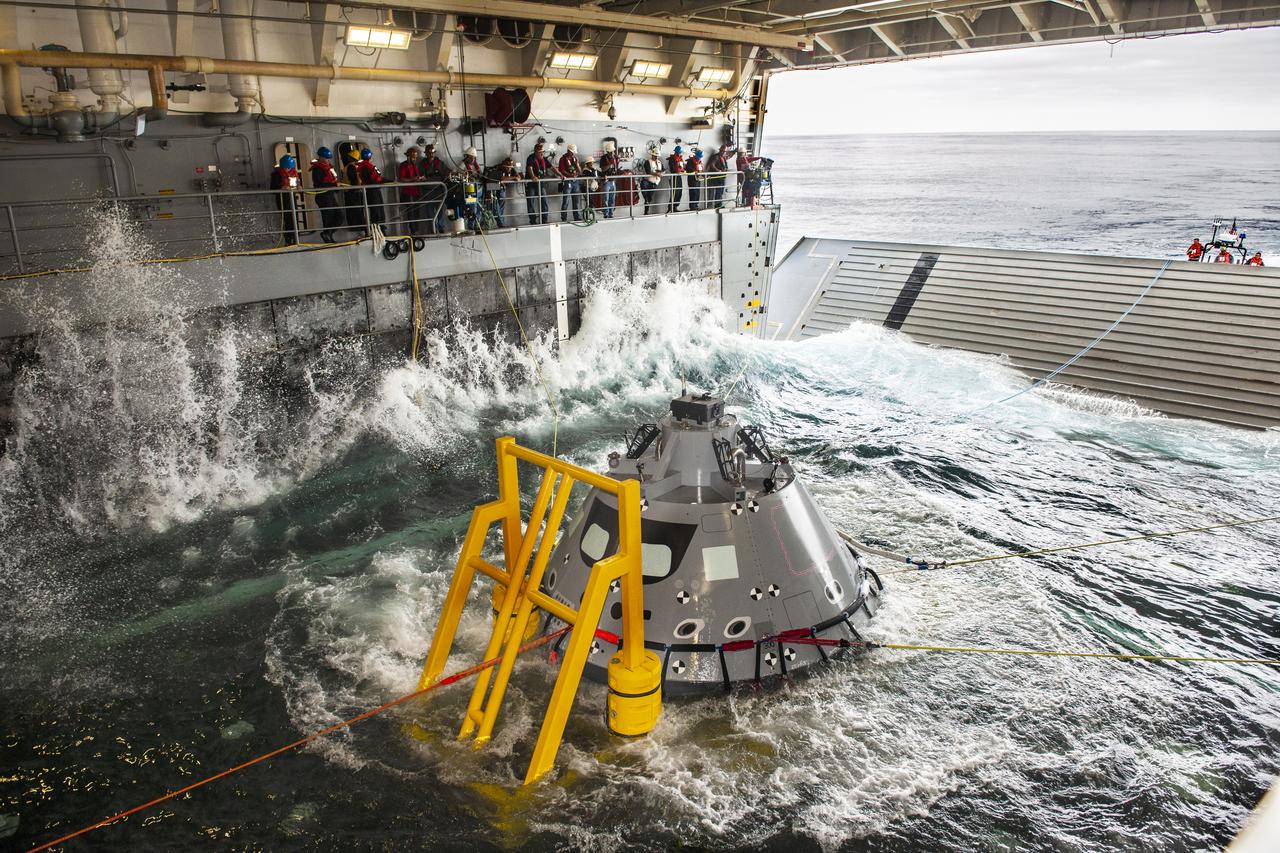 NASA Recovery Team members watch as a test version of the Orion capsule is pulled into the flooded well deck of the USS John P. Murtha, during Underway Recovery Test-7 (URT-7) on Oct. 30, 2018. URT-7 is one in a series of tests that the Exploration Ground Systems Recovery Team, along with the U.S. Navy, are conducting to verify and validate procedures and hardware that will be used to recover the Orion spacecraft after it splashes down in the Pacific Ocean following deep space exploration missions. Orion will have emergency abort capability, sustain the crew during space travel and provide safe re-entry from deep space return velocities.
