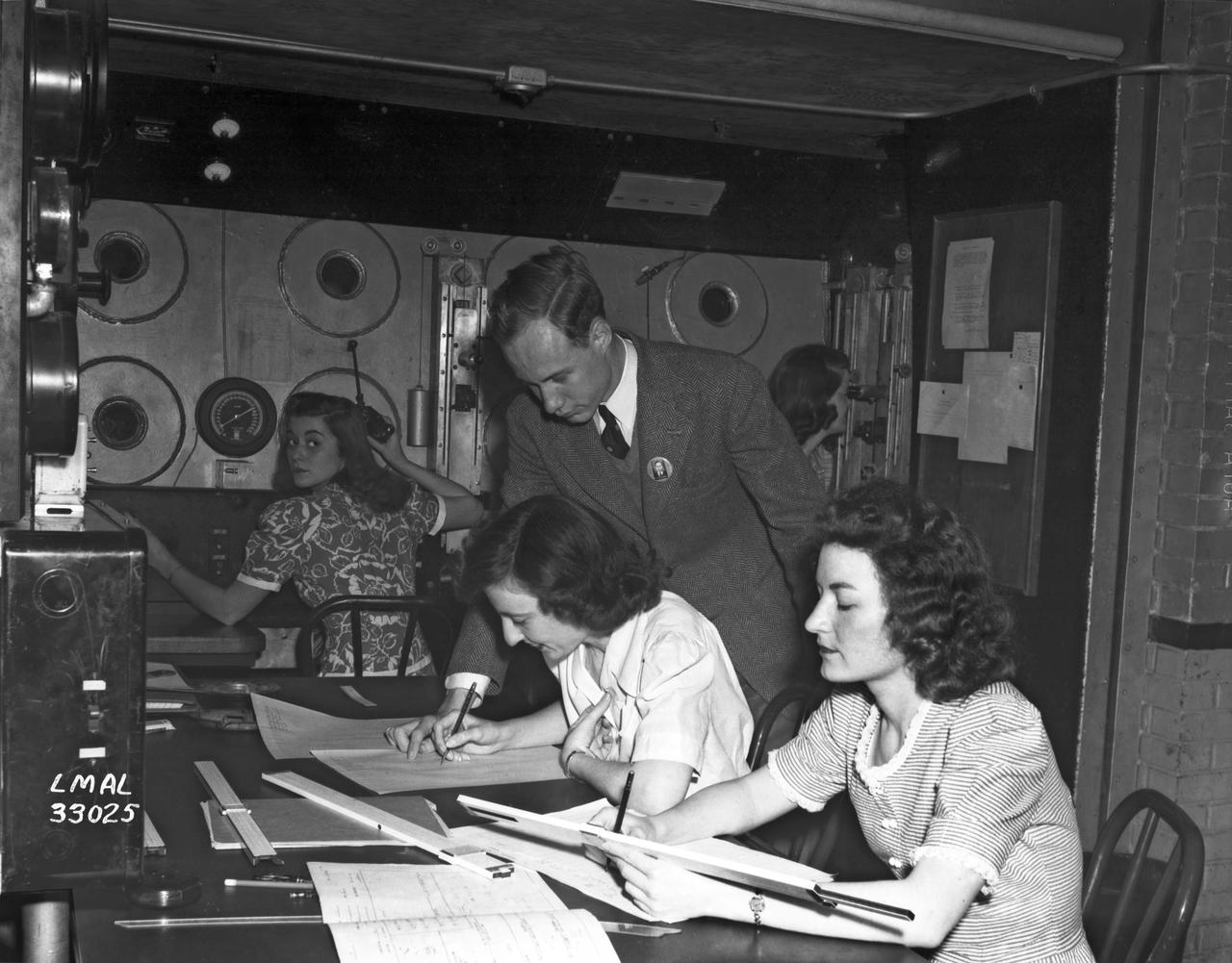 In the picture are F.F. Fullmer, aeronautical engineer, supervise a group of women who are helping operate the research equipment in the two-dimensional wind tunnel. Miss Elizabeth Patterson, left foreground, and Miss Katherine Thomason, right foreground obtains aerodynamic data, while Miss Lenore Woodland left background and Mrs. Blanche White help operate the tunnel. By Lee Dickinson 1943 