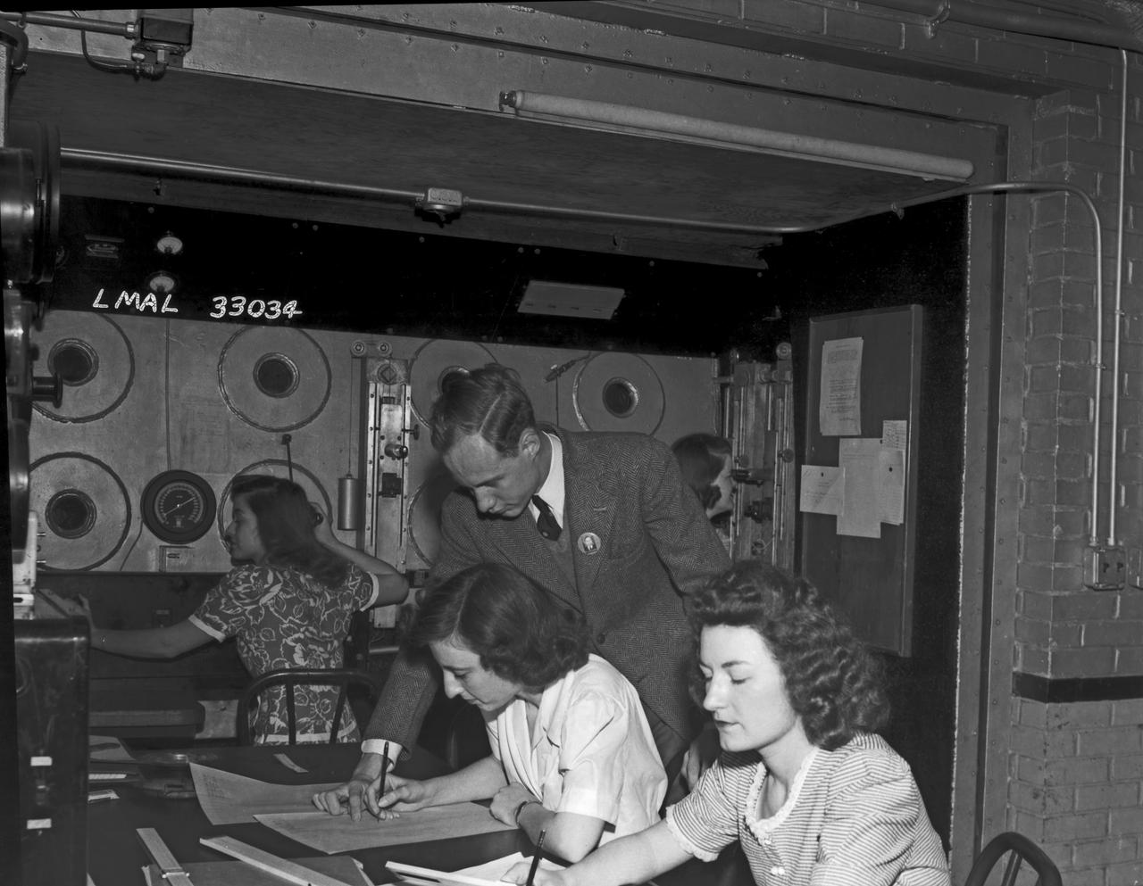 Women Adequately Filling Posts In NACA Laboratory:  In the picture are F.F. Fullmer, aeronautical engineer, supervise a group of women who are helping operate the research equipment in the two-dimensional wind tunnel. Miss Elizabeth Patterson, left foreground, and Miss Katherine Thomason, right foreground obtains aerodynamic data, while Miss Lenore Woodland left background and Mrs. Blanche White help operate the tunnel. By Lee Dickinson 1943 