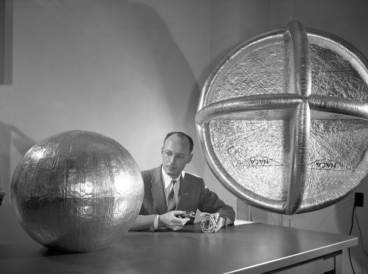 L57-525 Engineer W.J. O Sullivan, Jr., looks at inflated 20 inch subsatellite while holding inflation bottle and folded duplicate copy, February 1957. Photograph published in A New Dimension  Wallops Island Flight Test Range: The First Fifteen Years by Joseph Shortal. A NASA publication. Page 601.