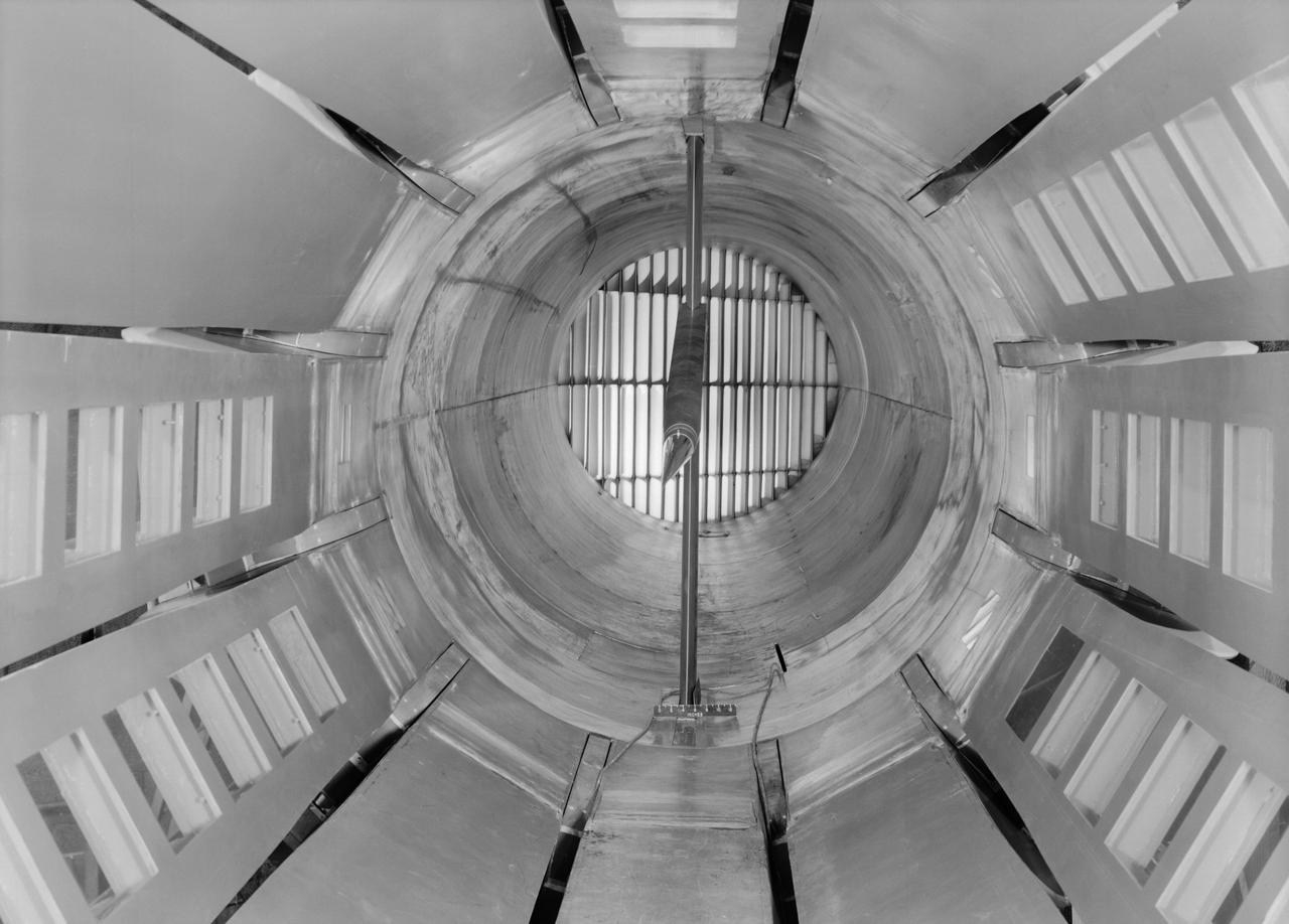  Interior view of the slotted throat test section installed in the 8-Foot High Speed Tunnel (HST) in 1950.  The slotted region is about 160 inches in length. In this photograph, the sting-type model support is seen straight on. In a NASA report, the test section is described as follows:  The test section of the Langley 8-foot transonic tunnel is dodecagonal in cross section and has a cross-sectional area of about 43 square feet. Longitudinal slots are located between each of the 12 wall panels to allow continuous operation through the transonic speed range. The slots contain about 11 percent of the total periphery of the test section. Six of the twelve panels have windows in them to allow for schlieren observations. The entire test section is enclosed in a hemispherical shaped chamber.  John Becker noted that the tunnel s  final achievement was the development and use in routine operations of the first transonic slotted throat. The investigations of wing-body shapes in this tunnel led to Whitcomb s discovery of the transonic area rule.  James Hansen described the origins of the the slotted throat as follows:  In 1946 Langley physicist Ray H. Wright conceived a way to do transonic research effectively in a wind tunnel by placing slots in the throat of the test section. The concept for what became known as the slotted-throat or slotted-wall tunnel came to Wright not as a solution to the chronic transonic problem, but as a way to get rid of wall interference (i.e., the mutual effect of two or more meeting waves or vibrations of any kind caused by solid boundaries) at subsonic speeds.  For most of the year before Wright came up with this idea, he had been trying to develop a theoretical understanding of wall interference in the 8-Foot HST, which was then being repowered for Mach 1 capability.  When Wright presented these ideas to John Stack, the response was enthusiastic but neither Wright nor Stack thought of slotted-throats as a solution to the transonic problem, only the wall interference problem.  It was an accidental discovery which showed that slotted throats might solve the transonic problem. Most engineers were skeptical but Stack persisted. Initially, plans were to modify the 16-Foot tunnel but in the spring of 1948, Stack announced that the 8-Foot HST would also be modified. As Hansen notes:  The 8-Foot HST began regular transonic operations for research purposes on 6 October 1950.  The concept was a success and led to plans for a new wind tunnel which would be known as the 8-Foot Transonic Pressure Tunnel. -- Published in U.S., National Advisory Committee for Aeronautics,  Characteristics of Nine Research Wind Tunnels of the Langley Aeronautical Laboratory,  1957, pp. 17, 22  James R. Hansen, Engineer in Charge, NASA SP-4305, p. 454 and Chapter 11,  The Slotted Tunnel and the Area Rule. 