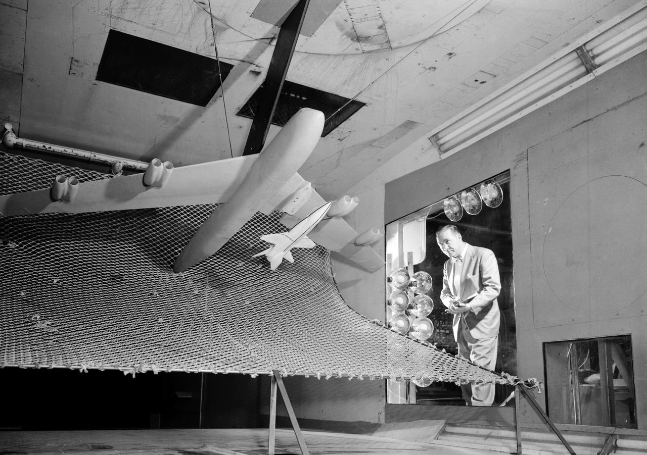 A one-twentieth scale model of the X-15  originally suspended beneath the wing of a B-52 is observed by a scientist of the National Aeronautics and Space Administration (NASA) as it leaves the bomber model in tests to determine the release characteristics and drop motion of the research airplane. Caption:  The aerodynamics of air launching the North American X-15 being investigated in the 300MPH Low Speed 7x10 Tunnel, about 1957.  Photograph published in Engineer in Charge: A History of the Langley Aeronautical Laboratory, 1917-1958 by James R. Hansen. Page 366. Photograph also published in Sixty Years of Aeronautical Research 1917-1977 By David A. Anderton. A NASA publication. Page 49.