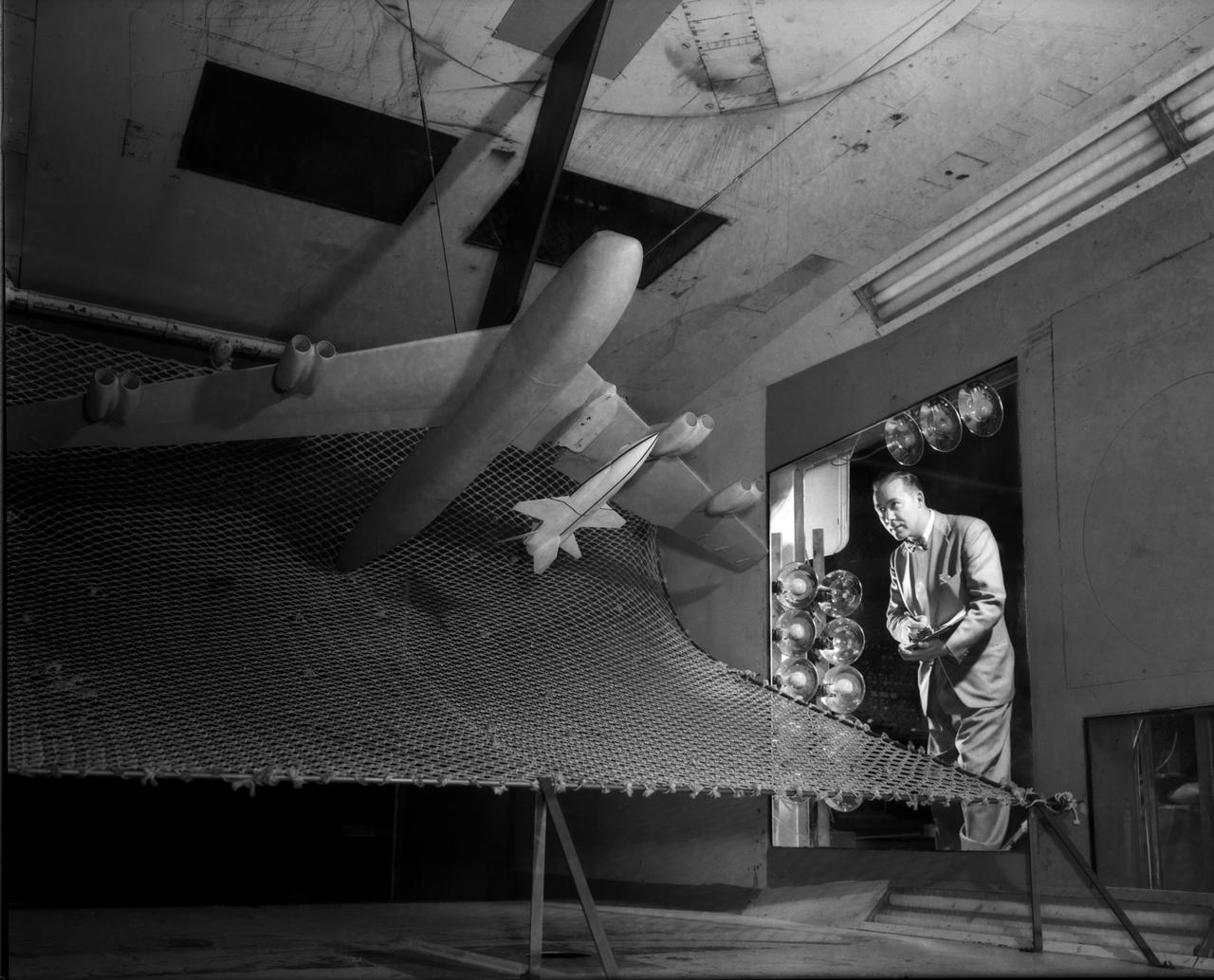 A one-twentieth scale model of the X-15  originally suspended beneath the wing of a B-52 is observed by a scientist of the National Aeronautics and Space Administration (NASA) as it leaves the bomber model in tests to determine the release characteristics and drop motion of the research airplane. Caption:  The aerodynamics of air launching the North American X-15 being investigated in the 300MPH Low Speed 7x10 Tunnel, about 1957.  Photograph published in Engineer in Charge: A History of the Langley Aeronautical Laboratory, 1917-1958 by James R. Hansen. Page 366. Photograph also published in Sixty Years of Aeronautical Research 1917-1977 By David A. Anderton. A NASA publication. Page 49.
