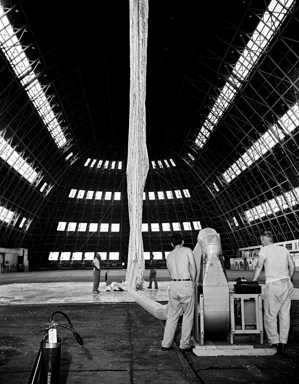 Inflation Tests of the Echo 1 Satellite in Weeksville, N.C.  1958-L-03603 Image Langley engineers Edwin Kilgore (center), Norman Crabill (right) and an unidentified man take a peek inside the vast balloon during inflation tests.  Page. 183 Space Flight Revolution NASA Langley Research Center From Sputnik to Apollo. NASA SP-4308. 
