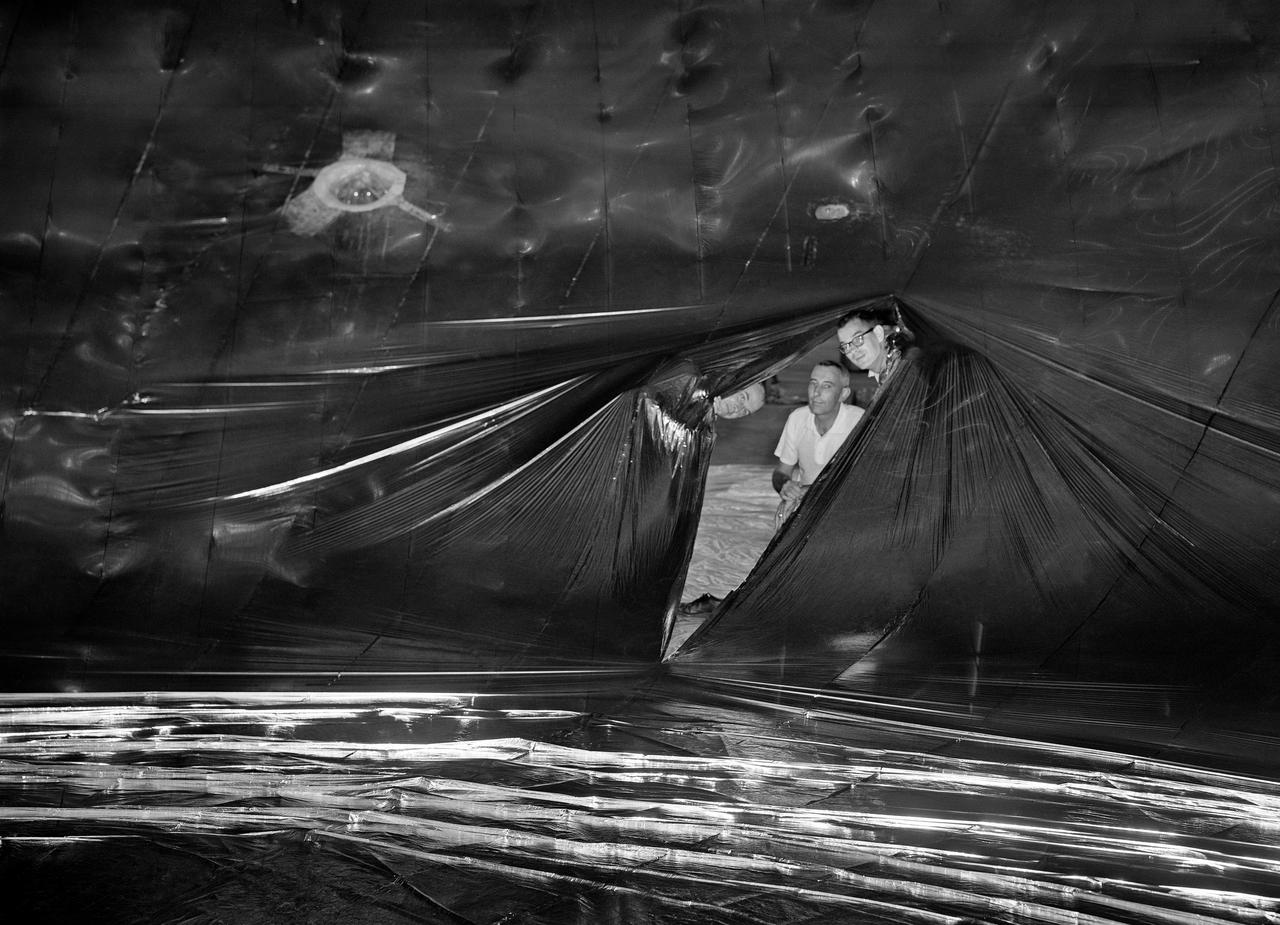 Inflation Tests of the Echo 1 Satellite in Weeksville, N.C.  1958-L-03603 Image Langley engineers Edwin Kilgore (center), Norman Crabill (right) and an unidentified man take a peek inside the vast balloon during inflation tests.  Page. 183 Space Flight Revolution NASA Langley Research Center From Sputnik to Apollo. NASA SP-4308. 