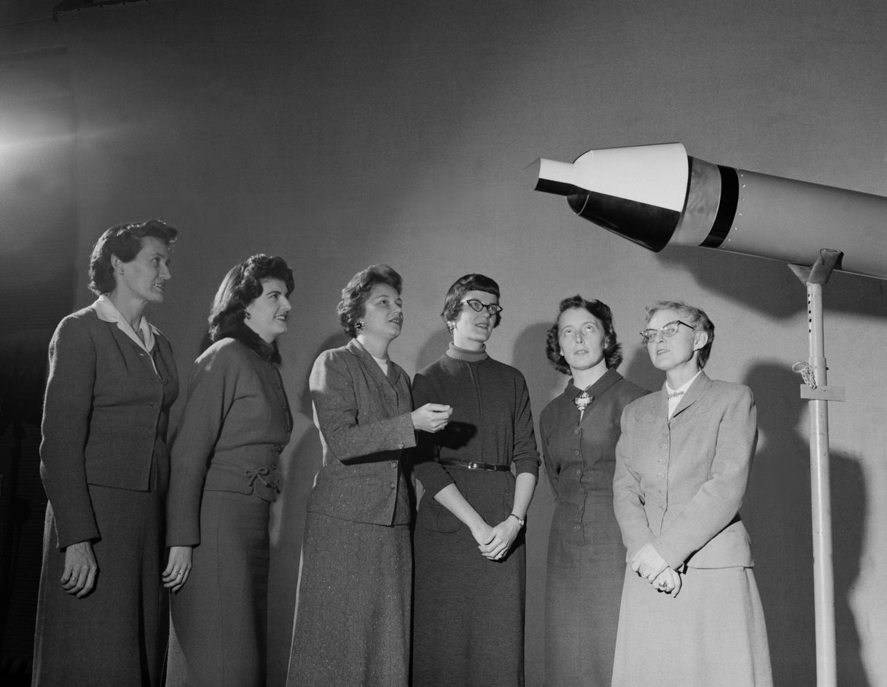 Women Scientists: Lucille Coltrane, Jean Clark Keating, Katherine Cullie Speegle, Doris 'Dot' Lee, Ruth Whitman, and Emily Stephens Mueller,Lucille Coltrane is at the far left. She was a computer and worked for Norm Crabill who provided positive identification. Lucille authored a NACA Research Memorandum, Investigation of Two Bluff Shapes in Axial Free Flight Over a Mach Number Range From 0.35 to 2.15 in 1958.  Next to Lucille is Jean Clark Keating. Jean was identified by Mary Woerner who said that both Jean and her husband Jerry are now deceased.  The third woman from the left is Katherine Cullie Speegle. Katherine co-authored two research papers: Preliminary Results From a Free-Flight Investigation of Boundary-Layer Transition and Heat Transfer on a Highly Polished 8-Inch-Diameter Hemisphere-Cylinder at Mach Numbers up to 3 and Reynolds Numbers Based on a Length of 1 Foot up to 17.7 x 10 to the 6th and Heat Transfer For Mach Numbers Up to 2.2 and Pressure Distributions for Mach Numbers Up to 4.7 From Flight Investigations of a Flat-Face Cone and a Hemisphere-Cone.  Norm remembered the woman standing as Doris. Mary Alice identified her as Doris 'Dot' Lee, who worked with Katherine Speegle. Dot was married to a NASA engineer named John Lee.  Next to Doris is Ruth Whitman. Norm remembered she and her husband owned a Howard DGA 15 at the airport in WEst Point. That prompted Mary Alice to remember her name and that her husband was Jim.  The woman seated on the right is Emily Stephens Mueller. Norm remembers that Emily went to Houston as part of the Space Task Group, but retired back here on the peninsula. In 2008, Emily attended the NACA Reunion X11. She walked over to a table of books about the history of NACA, former NACA facilities and the organization's aviation pioneers and saw a book about women of flight from the Dryden Research Center and paused, then pointed somewhat in amazement. "That’s me," she said of a picture on the cover of her on the far left of a li