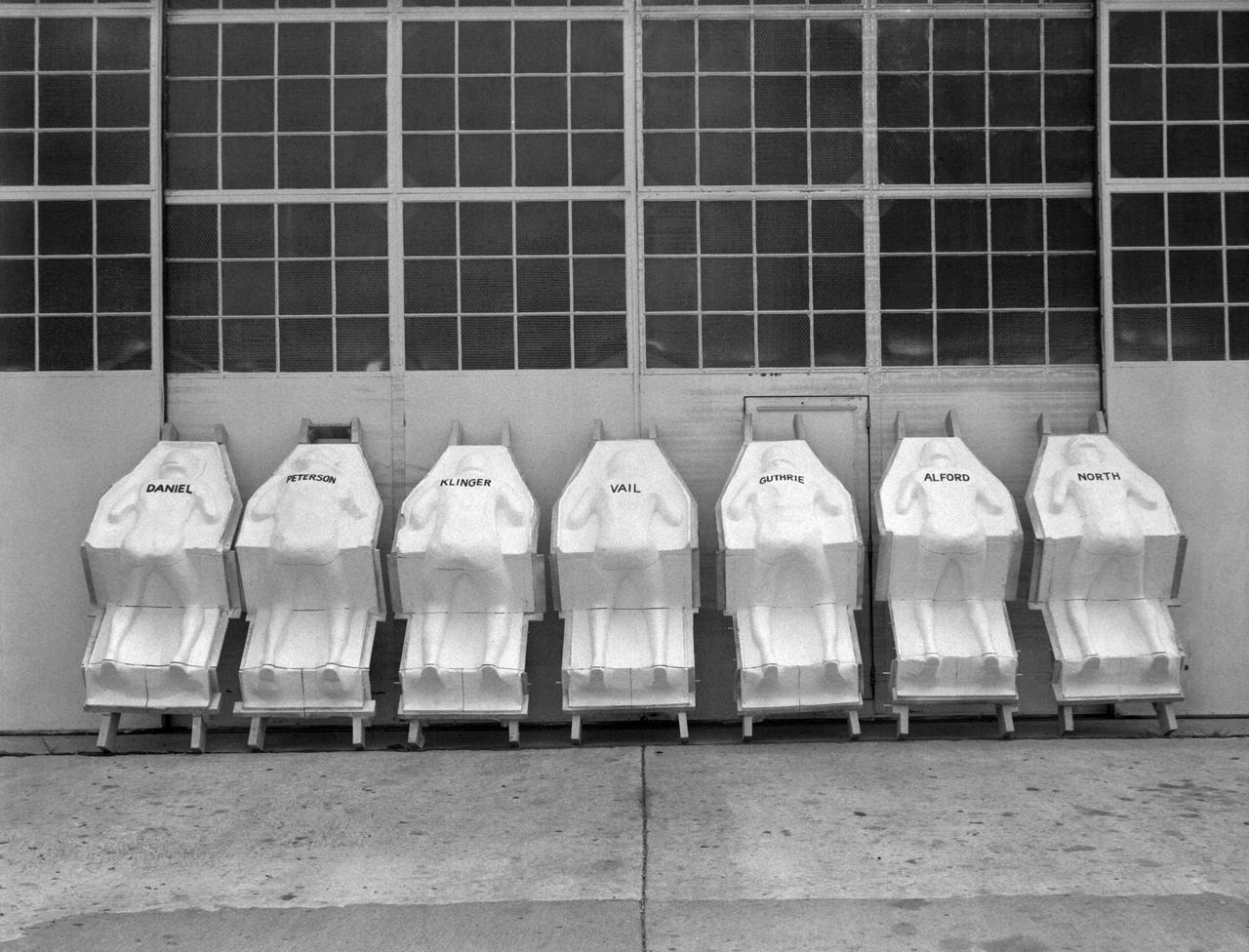 Molds for couches for test pilots, line the NASA Langley Research Centers model shop wall. The names of the test subjects (Langley employees) are written on the back.  The couches are similar to those made for each astronaut and fitted into the Mercury capsules for manned spaceflight.