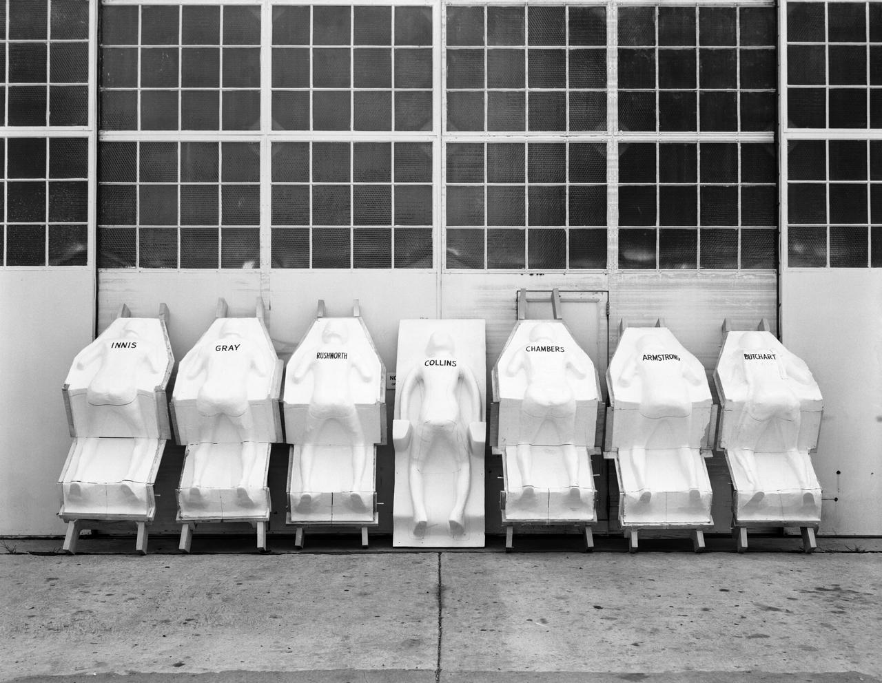 Molds for couches for test pilots, line the NASA Langley Research Centers model shop wall. The names of the test subjects (Langley employees) are written on the back.  The couches are similar to those made for each astronaut and fitted into the Mercury capsules for manned spaceflight.
