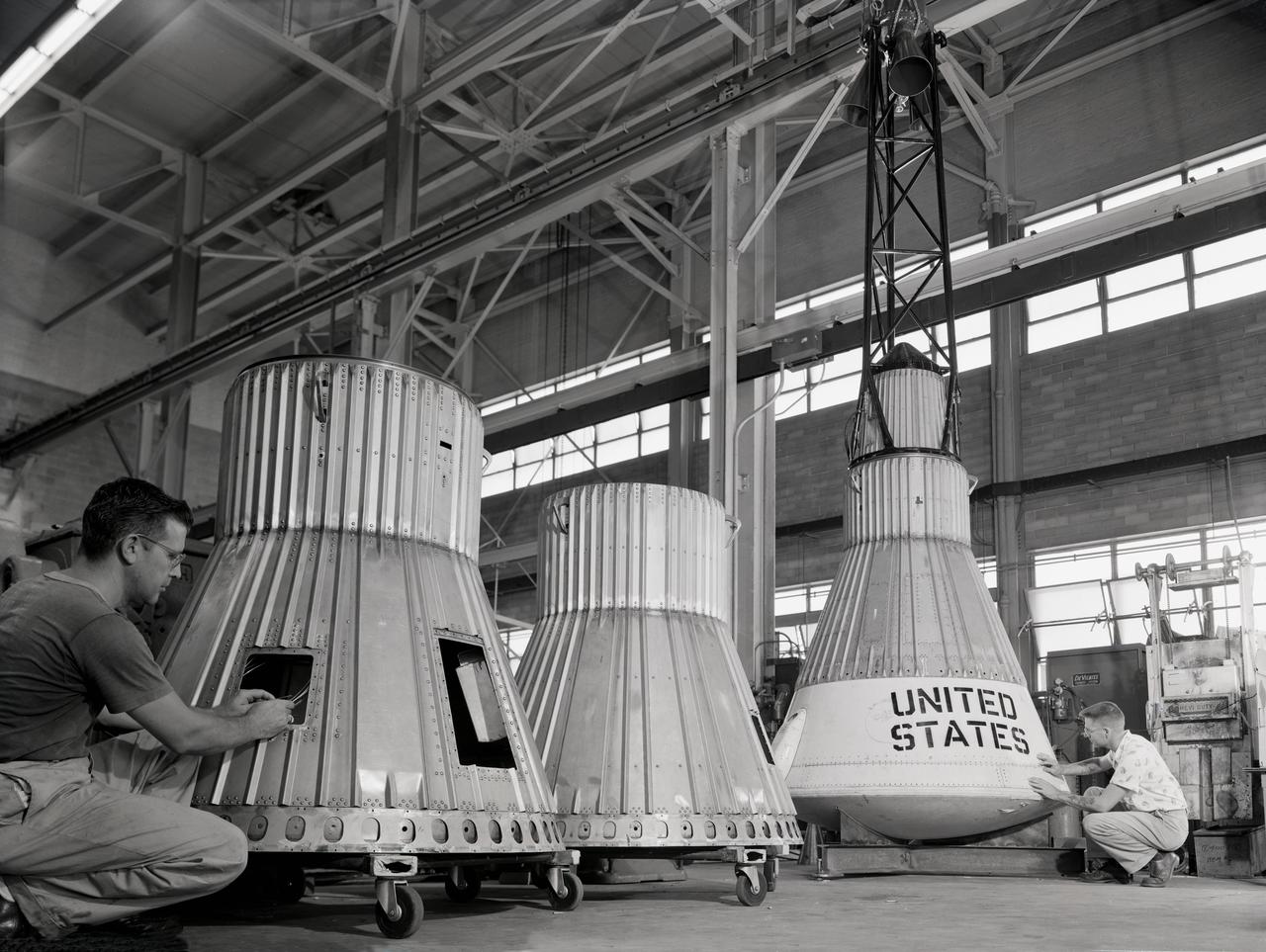 Assembling the Little Joe capsules.  The capsules were manufactured  in-house  by Langley technicians. Three capsules are shown here in various stages of assembly. The escape tower and rocket motors shown on the completed capsule would be removed before shipping and finally assembly for launching at Wallops Island. Joseph Shortal wrote (vol. 3, p. 32):  Design of the Little Joe capsules began at Langley before McDonnell started on the design of the Mercury capsule and was, therefore, a separate design. Although it was not designed to carry a man, it did have to carry a monkey. It had to meet the weight and center of gravity requirements of Mercury and withstand the same aerodynamic loads during the exit trajectory.   Although in comparison with the overall Mercury Project, Little Joe was a simple undertaking, the fact that an attempt was made to condense a normal two-year project into a 6-month one with in house labor turned it into a major undertaking for Langley.  Project Mercury: Little Joe: Boilerplate Mercury spacecraft undergo fabrication at the shops of the Langley Research Center. They will launched atop Little Joe rockets to test the spacecraft recovery systems. -- Published in Joseph A. Shortal, History of Wallops Station: Origins and Activities Through 1949, (Wallops Island, VA: National Aeronautics and Space Administration, Wallops Station, nd), Comment Edition. L59-4947 Technicians prepare a Little Joe launch vehicle prototype for the Mercury space program, 1959. Photograph published in Winds of Change, 75th Anniversary NASA publication, page 76, by James Schultz
