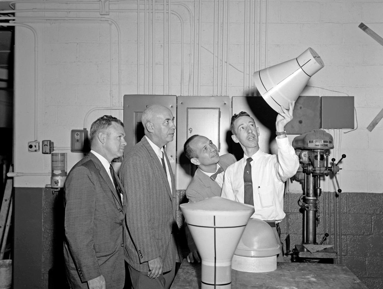 From left to right: Charles Donlan, deputy head, and Robert Gilruth, head of STG, look at a scale model of a Mercury space capsule.
