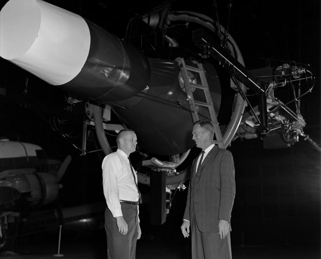 Astronaut Neil Armstrong (left) was one of 14 astronauts, 8 NASA test pilots, and 2 McDonnell test pilots who took part in simulator studies. Armstrong was the first astronaut to participate (November 6, 1963). A.W. Vogeley described the simulator in his paper "Discussion of Existing and Planned Simulators For Space Research," "Many of the astronauts have flown this simulator in support of the Gemini studies and they, without exception, appreciated the realism of the visual scene. The simulator has also been used in the development of pilot techniques to handle certain jet malfunctions in order that aborts could be avoided. In these situations large attitude changes are sometimes necessary and the false motion cues that were generated due to earth gravity were somewhat objectionable; however, the pilots were readily able to overlook these false motion cues in favor of the visual realism." Roy F. Brissenden, noted in his paper "Initial Operations with Langley's Rendezvous Docking Facility," "The basic Gemini control studies developed the necessary techniques and demonstrated the ability of human pilots to perform final space docking with the specified Gemini-Agena systems using only visual references. ... Results... showed that trained astronauts can effect the docking with direct acceleration control and even with jet malfunctions as long as good visual conditions exist.... Probably more important than data results was the early confidence that the astronauts themselves gained in their ability to perform the maneuver in the ultimate flight mission." Francis B. Smith, noted in his paper "Simulators for Manned Space Research," "Some major areas of interest in these flights were fuel requirements, docking accuracies, the development of visual aids to assist alignment of the vehicles, and investigation of alternate control techniques with partial failure modes. However, the familiarization and confidence developed by the astronaut through flying and safely docking the simulator during these tests was one of the major contributions. For example, it was found that fuel used in docking from 200 feet typically dropped from about 20 pounds to 7 pounds after an astronaut had made a few training flights." -- Published in Barton C. Hacker and James M. Grimwood, On the Shoulders of Titans: A History of Project Gemini, NASA SP-4203; A.W. Vogeley, "Discussion of Existing and Planned Simulators For Space Research," Paper presented at the Conference on the Role of Simulation in Space Technology, August 17-21, 1964; Roy F. Brissenden, "Initial Operations with Langley's Rendezvous Docking Facility," Langley Working Paper, LWP-21, 1964; Francis B. Smith, "Simulators for Manned Space Research," Paper presented at the 1966 IEEE International convention, March 21-25, 1966.