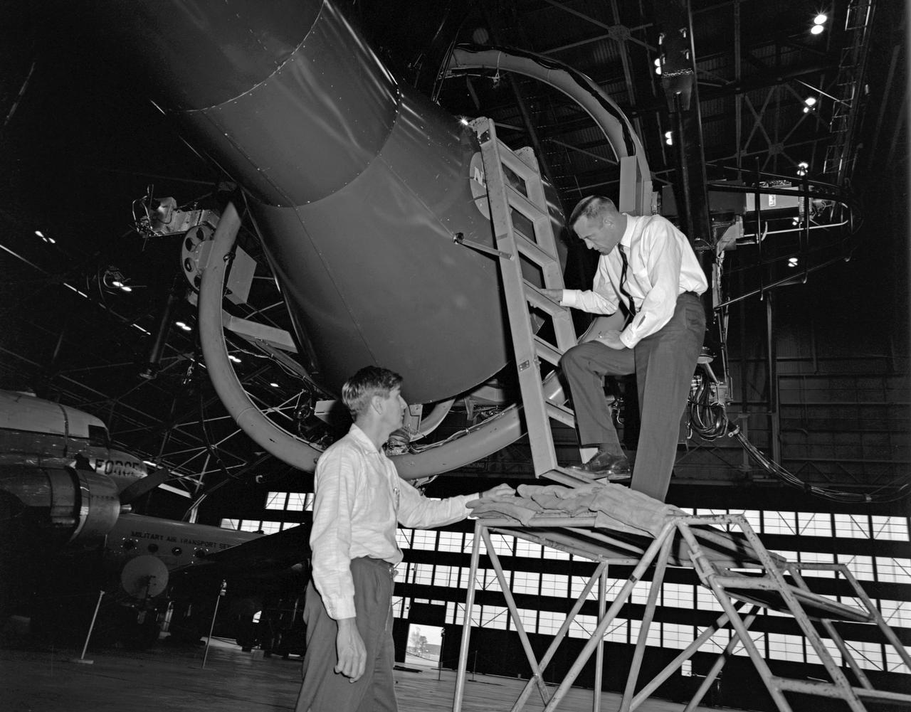 Astronaut Alan Shepard (right) was one of 14 astronauts, 8 NASA test pilots, and 2 McDonnell test pilots who took part in simulator studies. Shepard flew the simulator on November 14, 1963. A.W. Vogeley wrote: "Many of the astronauts have flown this simulator in support of the Gemini studies and they, without exception, appreciated the realism of the visual scene. The simulator has also been used in the development of pilot techniques to handle certain jet malfunctions in order that aborts could be avoided. In these situations large attitude changes are sometimes necessary and the false motion cues that were generated due to earth gravity were somewhat objectionable; however, the pilots were readily able to overlook these false motion cues in favor of the visual realism." Roy F. Brissenden noted that: "The basic Gemini control studies developed the necessary techniques and demonstrated the ability of human pilots to perform final space docking with the specified Gemini-Agena systems using only visual references. ... Results... showed that trained astronauts can effect the docking with direct acceleration control and even with jet malfunctions as long as good visual conditions exist.... Probably more important than data results was the early confidence that the astronauts themselves gained in their ability to perform the maneuver in the ultimate flight mission." Shepard commented: "I had the feeling tonight - a couple of times - that I was actually doing the space mission instead of the simulation. As I said before, I think it is a very good simulation." Shepard also commented on piloting techniques. Most astronauts arrived at this same preferred technique: Shepard: "I believe I have developed the preferred technique for these conditions and the technique appeared to me to be best was to come in slightly above the target so that I was able to use the longitudinal marks on the body of the target as a reference, particularly for a lateral translation and, of course, I used the foreshortening effect for a vertical translation, and this appeared to give me the best results. By that I mean the least number of control motions and the lowest fuel usage and the best end techniques, or the best end conditions, I should say." Engineer: "When you started to run you didn't start thrusting immediately I don't believe. It looked like you started working on your attitudes, then started closing in." Shepard: "That is correct. I did that because I felt that I wanted to get the X-axis translation in the most effective vector and for minimum fuel usage that wouldn't introduce any other lateral or vertical offsets that did not already exist." -- Published in Barton C. Hacker and James M. Grimwood, On the Shoulders of Titans: A History of Project Gemini, NASA SP-4203; A.W. Vogeley, "Discussion of Existing and Planned Simulators For Space Research," Paper presented at the Conference on the Role of Simulation in Space Technology, August 17-21, 1964; Roy F. Brissenden, "Initial Operations with Langley's Rendezvous Docking Facility," Langley Working Paper, LWP-21, 1964.