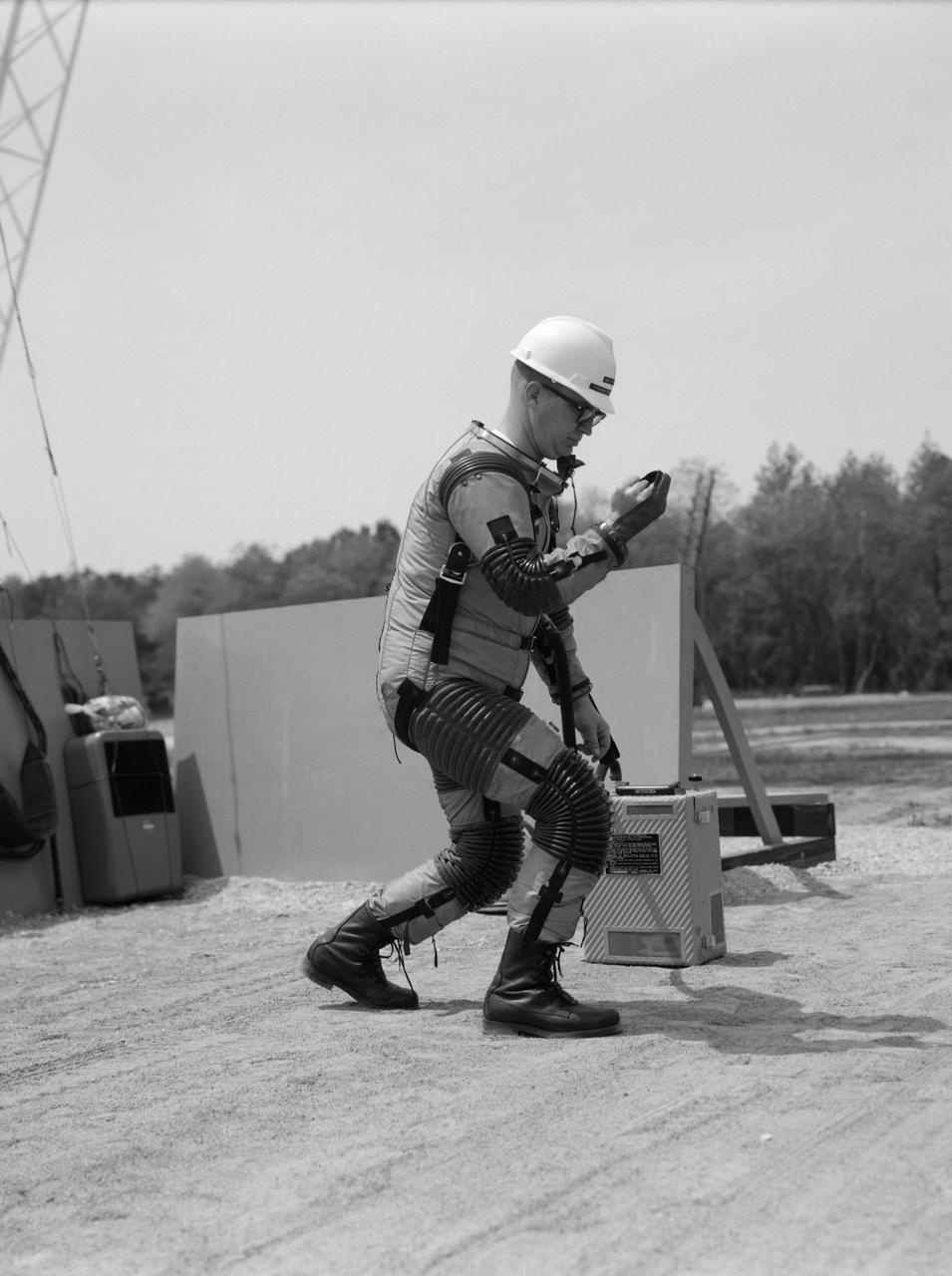 Special "space" suit for the Reduced Gravity Walking Simulator located at the Lunar Landing Facility. The purpose of this simulator was to study the subject while walking, jumping or running. Researchers conducted studies of various factors such as fatigue limit, energy expenditure, and speed of locomotion. A.W. Vigil described the purpose of the simulator in his paper "Discussion of Existing and Planned Simulators for Space Research," "When the astronauts land on the moon they will be in an unfamiliar environment involving, particularly, a gravitational field only one-sixth as strong as on earth. A novel method of simulating lunar gravity has been developed and is supported by a puppet-type suspension system at the end of a long pendulum. A floor is provided at the proper angle so that one-sixth of the subject's weight is supported by the floor with the remainder being supported by the suspension system. This simulator allows almost complete freedom in vertical translation and pitch and is considered to be a very realistic simulation of the lunar walking problem. For this problem this simulator suffers only slightly from the restrictions in lateral movement it puts on the test subject. This is not considered a strong disadvantage for ordinary walking problems since most of the motions do, in fact, occur in the vertical plane. However, this simulation technique would be severely restrictive if applied to the study of the extra-vehicular locomotion problem, for example, because in this situation complete six degrees of freedom are rather necessary. This technique, in effect, automatically introduces a two-axis attitude stabilization system into the problem. The technique could, however, be used in preliminary studies of extra-vehicular locomotion where, for example, it might be assumed that one axis of the attitude control system on the astronaut maneuvering unit may have failed." -- Published in James R. Hansen, Spaceflight Revolution: NASA Langley Research Center From Sputnik to Apollo, (Washington: NASA, 1995), p. 377; A.W. Vigil, "Discussion of Existing and Planned Simulators for Space Research," Paper presented at Conference on the Role of Simulation in Space Technology," Blacksburg, VA, August 17-21, 1964.