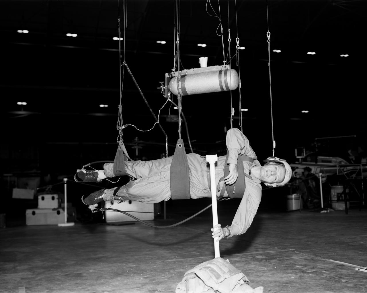Cable system which supports the test subject on the Reduced Gravity Walking Simulator. The purpose of this simulator was to study the subject while walking, jumping or running. Researchers conducted studies of various factors such as fatigue limit, energy expenditure, and speed of locomotion. A.W. Vigil described the purpose of the simulator as follows: "When the astronauts land on the moon they will be in an unfamiliar environment involving, particularly, a gravitational field only one-sixth as strong as on earth. A novel method of simulating lunar gravity has been developed and is supported by a puppet-type suspension system at the end of a long pendulum. A floor is provided at the proper angle so that one-sixth of the subject's weight is supported by the floor with the remainder being supported by the suspension system. This simulator allows almost complete freedom in vertical translation and pitch and is considered to be a very realistic simulation of the lunar walking problem. For this problem this simulator suffers only slightly from the restrictions in lateral movement it puts on the test subject. This is not considered a strong disadvantage for ordinary walking problems since most of the motions do, in fact, occur in the vertical plane. However, this simulation technique would be severely restrictive if applied to the study of the extra-vehicular locomotion problem, for example, because in this situation complete six degrees of freedom are rather necessary. This technique, in effect, automatically introduces a two-axis attitude stabilization system into the problem. The technique could, however, be used in preliminary studies of extra-vehicular locomotion where, for example, it might be assumed that one axis of the attitude control system on the astronaut maneuvering unit may have failed." -- Published in James R. Hansen, Spaceflight Revolution: NASA Langley Research Center From Sputnik to Apollo, (Washington: NASA, 1995); A.W. Vigil, "Discussion of Existing and Planned Simulators for Space Research," Paper presented at Conference on the Role of Simulation in Space Technology," Blacksburg, VA, August 17-21, 1964.