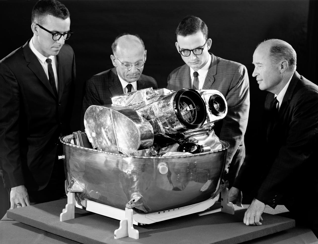 Lunar Orbiter was essentially a flying camera. The payload structure was built around a pressurized shell holding Eastman Kodak s dual-imaging photographic system, which used a camera with wide-angle and telephoto lenses that could simultaneously take two kinds of pictures on the same film.  Men in in the picture are: Right to left Cliff Nelson, Calvin Broome, Israel Taback and Joe Mooreman.  -- Published in James R. Hansen, Spaceflight Revolution: NASA Langley Research Center From Sputnik to Apollo, NASA SP-4308, p. 329.