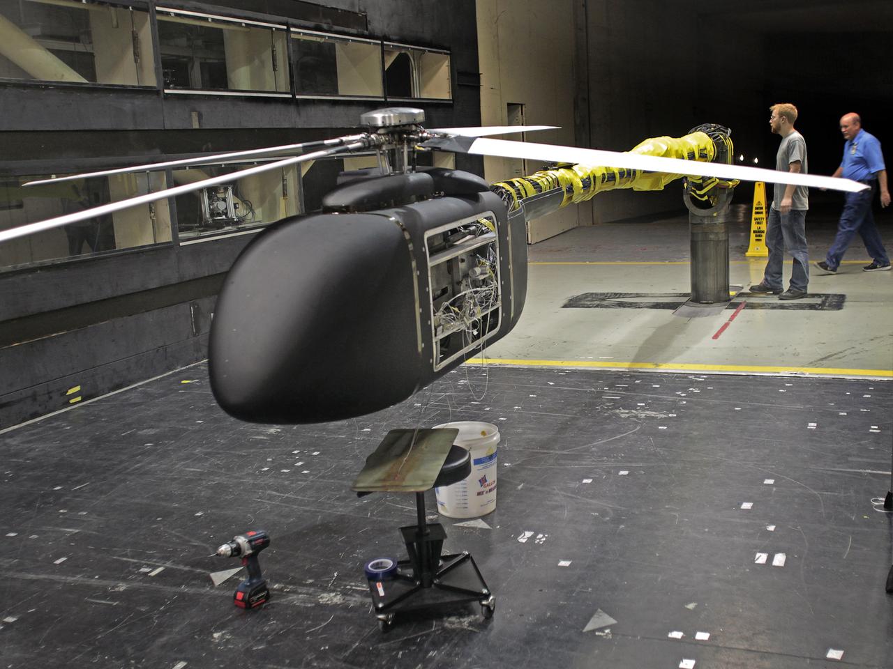 Helicopter active flow control tests in the 14X22 subsonic wind tunnel. Photos include preparation of the model before testing and the control room where testing is monitored and data collected