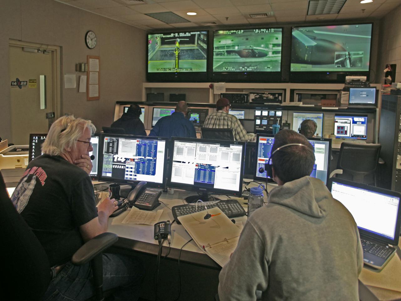 Helicopter active flow control tests in the 14X22 subsonic wind tunnel. Photos include preparation of the model before testing and the control room where testing is monitored and data collected