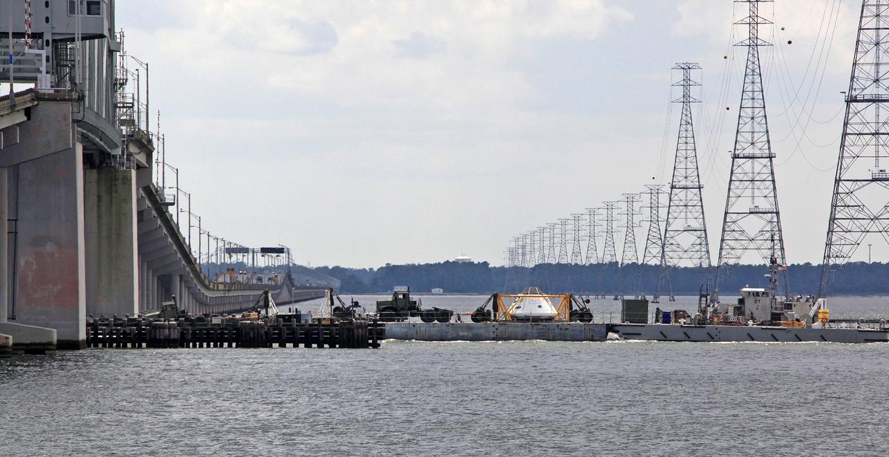 The Orion Test Capsule and a number of other items used in the capsule recovery at being transported down the James River on a Navy INLS "Improved Navy Lighterage System" from Fort Eustis from where it was loaded. Its liquid route will take them to Little Creek Amphibious Base in Norfolk, where it will stay until scheduled recovery test will be performed. 