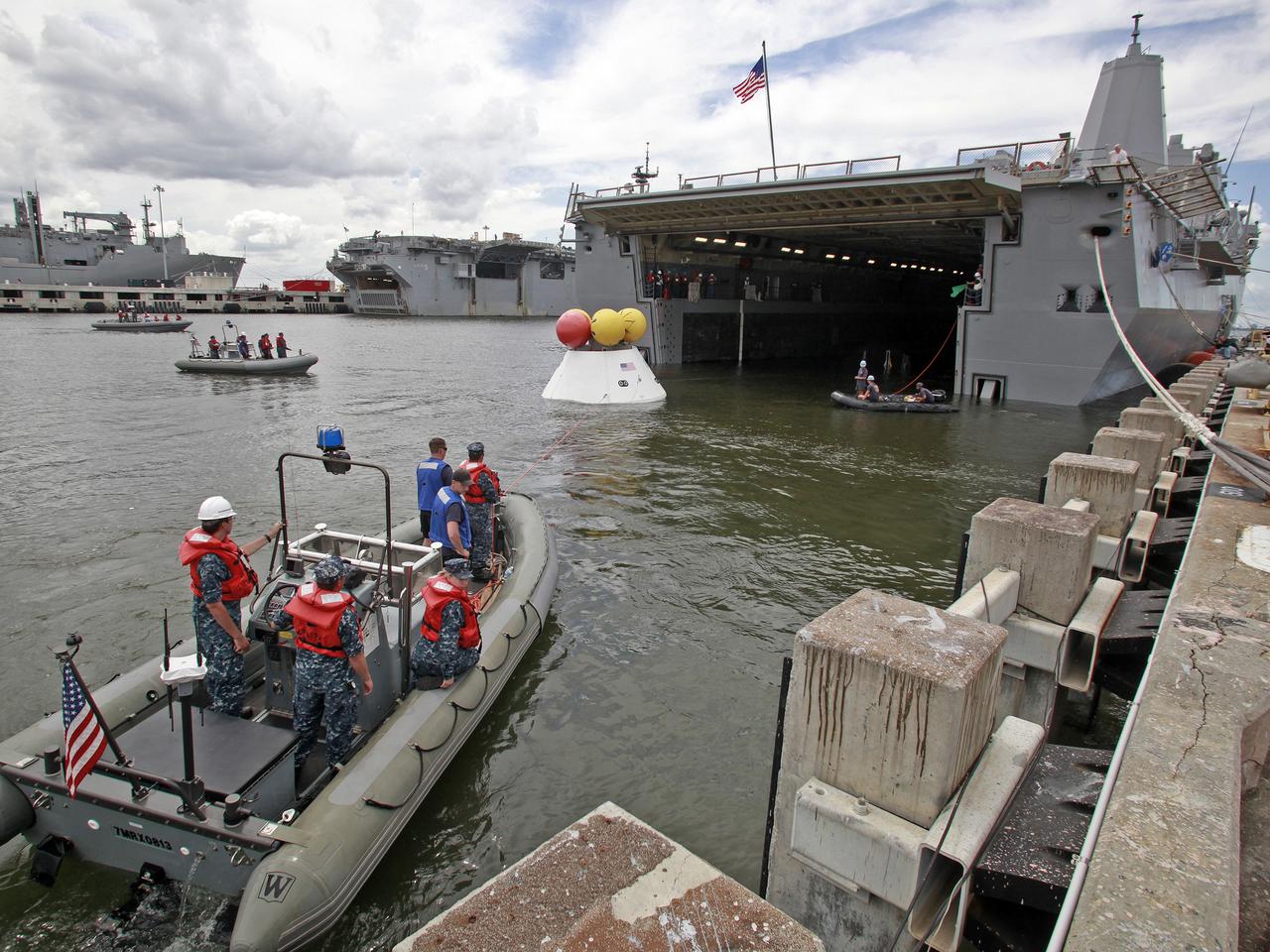 On August 15, 2013, at the Naval Station Norfolk near NASA’s Langley Research Center in Virginia, NASA and the U.S. Navy conducted a stationary recovery test on the Orion boilerplate test article in the water near a U.S. Navy ship. NASA and the U.S. Navy are conducting tests to prepare for recovery of the Orion crew module and forward bay cover on its return from a deep space mission. The stationary recovery tests allow the teams to demonstrate and evaluate the recovery processes, the hardware and the test personnel in a controlled environment. During the test, the U.S Navy Dive Team checked the capsule for hazards while sailors from the USS Arlington approached the capsule in inflatable boats, and towed it back to the ship’s flooded well deck. A second test will be conducted next year in the open waters of the Pacific Ocean.