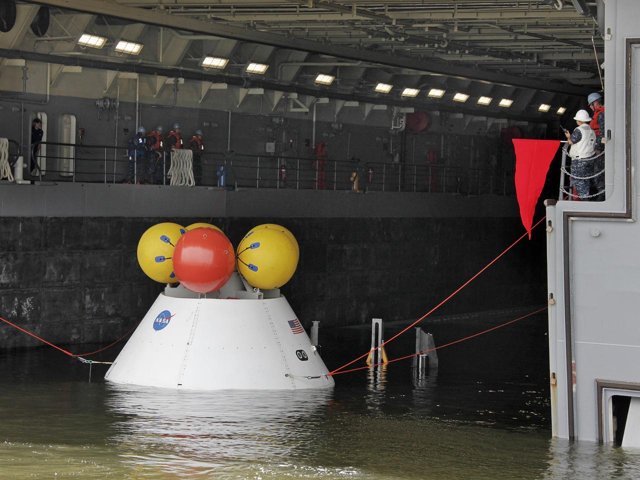 On August 15, 2013, at the Naval Station Norfolk near NASA’s Langley Research Center in Virginia, NASA and the U.S. Navy conducted a stationary recovery test on the Orion boilerplate test article in the water near a U.S. Navy ship. NASA and the U.S. Navy are conducting tests to prepare for recovery of the Orion crew module and forward bay cover on its return from a deep space mission. The stationary recovery tests allow the teams to demonstrate and evaluate the recovery processes, the hardware and the test personnel in a controlled environment. During the test, the U.S Navy Dive Team checked the capsule for hazards while sailors from the USS Arlington approached the capsule in inflatable boats, and towed it back to the ship’s flooded well deck. A second test will be conducted next year in the open waters of the Pacific Ocean.