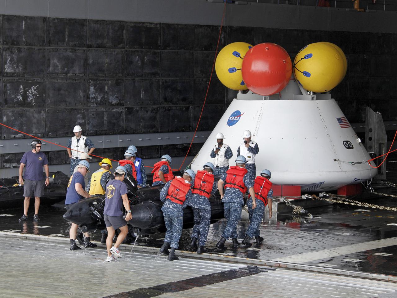 On August 15, 2013, at the Naval Station Norfolk near NASA’s Langley Research Center in Virginia, NASA and the U.S. Navy conducted a stationary recovery test on the Orion boilerplate test article in the water near a U.S. Navy ship. NASA and the U.S. Navy are conducting tests to prepare for recovery of the Orion crew module and forward bay cover on its return from a deep space mission. The stationary recovery tests allow the teams to demonstrate and evaluate the recovery processes, the hardware and the test personnel in a controlled environment. During the test, the U.S Navy Dive Team checked the capsule for hazards while sailors from the USS Arlington approached the capsule in inflatable boats, and towed it back to the ship’s flooded well deck. A second test will be conducted next year in the open waters of the Pacific Ocean.