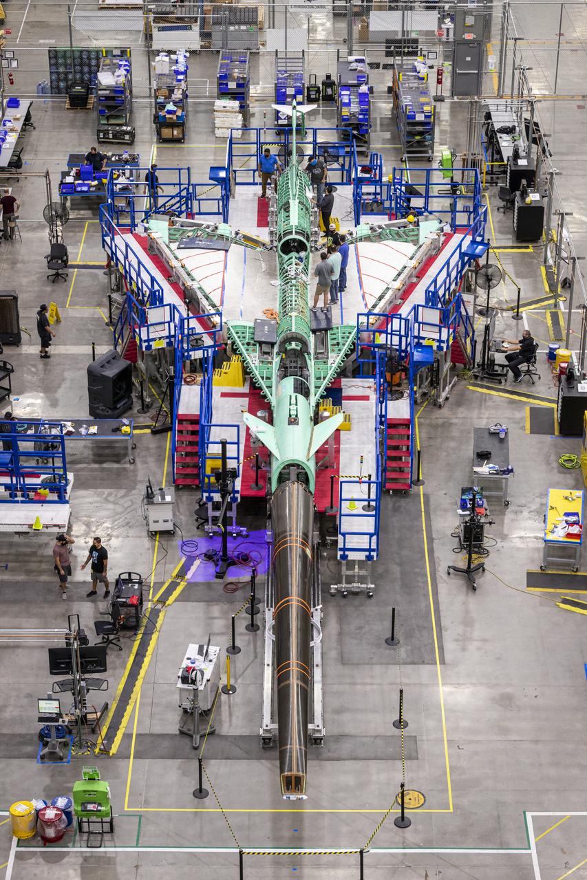 An overhead view of the X-59 supersonic plane with the tail on and the nose in the process of installation. The X-59’s nose is 38-feet long – approximately one third of the length of the entire aircraft. The aircraft, under construction at Lockheed Martin Skunk Works in Palmdale, California, will demonstrate the ability to fly supersonic while reducing the loud sonic boom to a quiet sonic thump.