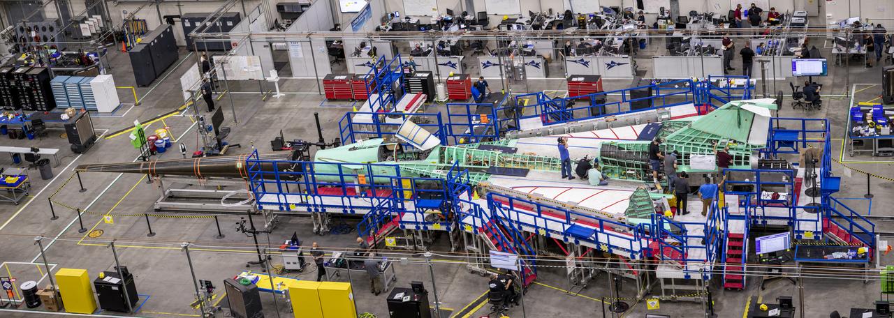 A panoramic side view of the left top of the X-59 supersonic plane with the tail on and the nose in the process of installation. The X-59’s nose is 38-feet long – approximately one third of the length of the entire aircraft. The aircraft, under construction at Lockheed Martin Skunk Works in Palmdale, California, will demonstrate the ability to fly supersonic while reducing the loud sonic boom to a quiet sonic thump.
