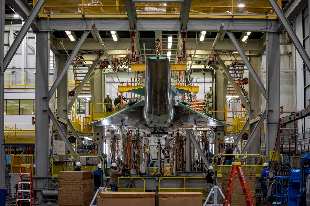 NASA’s X-59 is lowered into the test fixture as it prepares to undergo structural stress tests at  Lockheed Martin in Fort Worth, Texas. The X-59 is a one-of-a-kind airplane designed to fly at supersonic speeds without making a startling sonic boom sound for the communities below. This is part of NASA’s Quesst mission which plans to help  enable supersonic air travel over land.