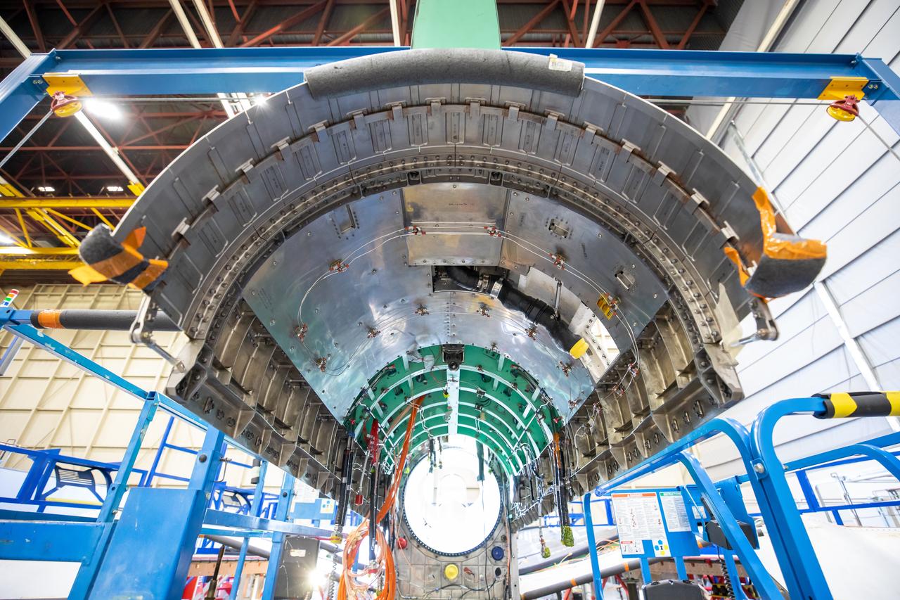 The upper empennage, or tail section of the plane, and engine bay is surrounded by a blue gantry that is used to assist with ground installation and removal of the X-59’s lower empennage and engine. Once fully assembled, the X-59 aircraft will demonstrate the ability to fly supersonic while reducing the loud sonic boom to a quiet sonic thump and help enable commercial supersonic air travel over land. This aircraft is the centerpiece of NASA’s Quesst mission. 