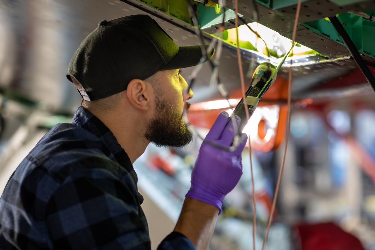 A Lockheed Martin Skunk Works technician inspects some of the wiring and sensors on the X-59 aircraft in preparation for the first power-on system checkouts.  Once complete, the X-59 aircraft will demonstrate the ability to fly supersonic while reducing the loud sonic boom to a quiet sonic thump and help enable commercial supersonic air travel over land. This aircraft is the centerpiece of NASA’s Quesst mission. 
