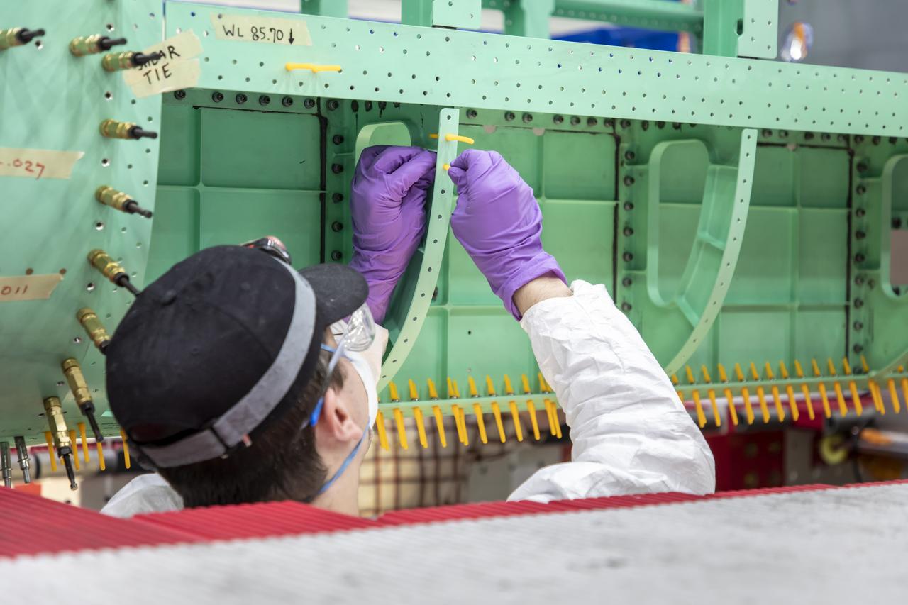 A Lockheed Martin technician prepares holes for installation of the fuselage panel on the X-59. The fuselage is the section of the aircraft that contains the cockpit. The aircraft, under construction at Lockheed Martin Skunk Works in Palmdale, California, will demonstrate the ability to fly supersonic while reducing the loud sonic boom to a quiet sonic thump.