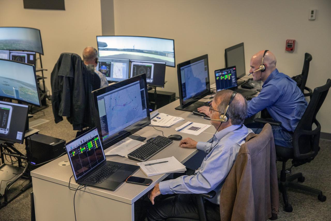 Focus on active photos –Class B Simulation Evaluation in the ATOL Lab at Langley (Also at FAA Tech Center) where team is working with one another in the lab, reviewing data on the monitors. Working the software, adjusting the software systems. Going over the shoulder to show the displays and screens as the software is running.   John Foster (left) in the role of an air taxi pilot in the simulator chair with Jim Chamberlain and Terence McClain at the flight manager stations running virtual air taxi integration simulations focusing on urban air space at NASA’s Langley Research Center in Hampton, Virginia on Sept. 25, 2024. 