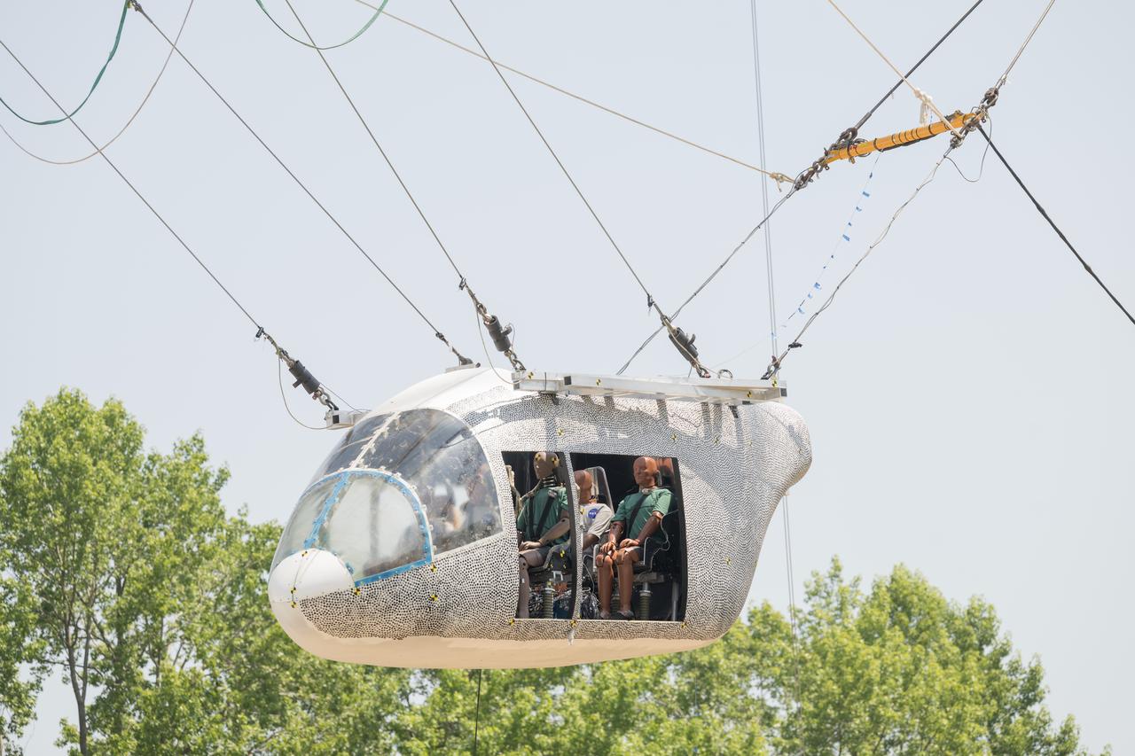 An aircraft body modeled after an air taxi with weighted test dummies inside is hoisted about 35 feet in the air by cables at NASA’s Langley Research Center in Hampton, Virginia. The aircraft was dropped from a tall steel structure, known as a gantry, on June 26 at Langley’s Landing and Impact Research Facility. NASA researchers are investigating aircraft materials that best absorb impact forces in a crash.
