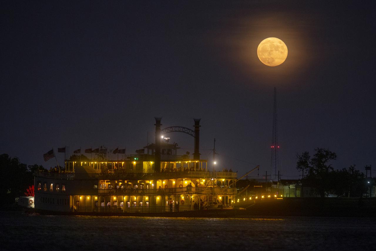 A paddlewheeler makes its way up the Mississippi River as the moon rises over New Orleans on Sunday evening, August 22, 2021. The August Sturgeon Moon, which was also a rare Blue Moon, was full at 7:02 A.M. local time Sunday but the nearly full moon still put on a show when it rose over New Orleans later that evening. New Orleans is home to the NASA Michoud Assembly Facility where the core stage of the Space Launch System that will return people to the moon is being built. Image credit: NASA/Michael DeMocker