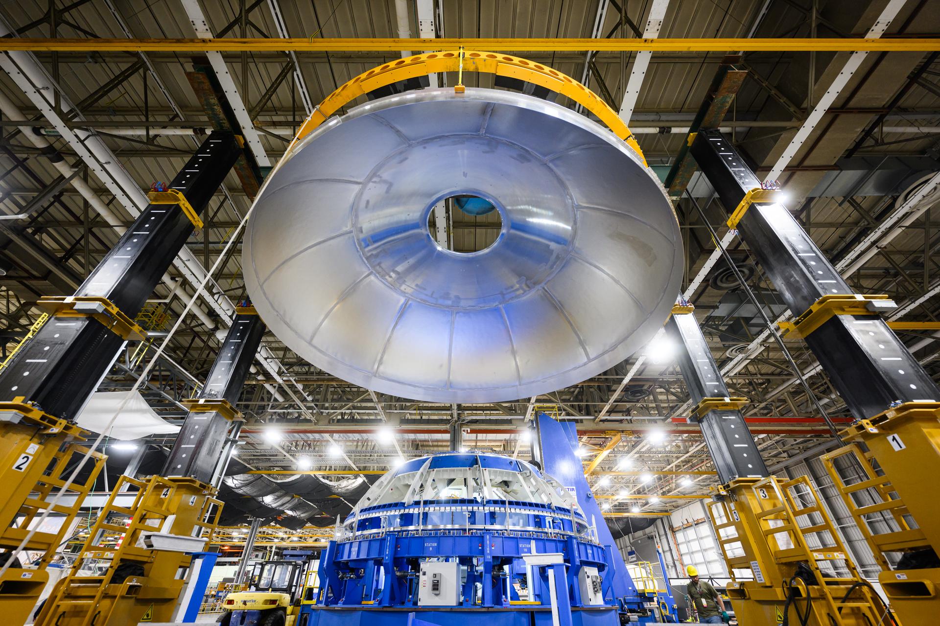 These images show technicians at NASA’s Michoud Assembly Facility in New Orleans removing a weld-confidence article from a robotic welding tool in December 2023. This article features pieces of a liquid hydrogen tank dome that were welded as a test to make sure the dome used for flight will be welded correctly. The dome will be part of the new, four-engine EUS (exploration upper stage) for NASA’s SLS (Space Launch System) rocket. EUS will be used for the Artemis IV lunar mission, replacing the single-engine interim cryogenic propulsion stage (ICPS) used for the first three Artemis missions. The evolved in-space stage will use a combination of liquid oxygen and liquid hydrogen propellants to help power the engines to send large cargo and crew inside NASA’s Orion spacecraft to the Moon. The weld-confidence article pictured here will not be used for flight but is instead helping teams prepare and certify the procedures needed to manufacture flight hardware. NASA is working to land the first woman and person of color on the Moon under Artemis. SLS is part of NASA’s backbone for deep space exploration, along with the Orion spacecraft, advanced spacesuits and rovers, the Gateway in orbit around the Moon, and commercial human landing systems. SLS is the only rocket that can send Orion, astronauts, and supplies to the Moon in a single launch.