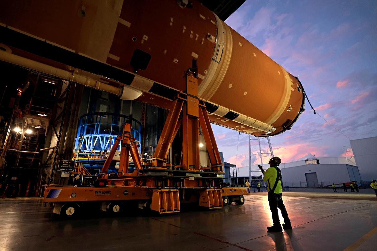 Technicians at Michoud Assembly Facility in New Orleans lift the core stage that will help launch the first crewed flight of NASA’s SLS (Space Launch System) rocket for the agency’s Artemis II mission. Teams at Michoud lifted the core stage on Thursday, July 11, 2024, onto NASA’s Multi-Purpose Transportation System, designed to transport SLS vehicle segments by waterway and roadway. It is tasked with transporting the vehicle from where it is manufactured to its intermediate test location and final launch destination. The core stage was lifted in preparation for its move onto the agency’s Pegasus barge, where it will be ferried to NASA’s Kennedy Space Center in Florida. Pegasus is maintained at Michoud. The core stage for the SLS mega rocket is the largest stage NASA has ever produced. At 212 feet tall, the stage consists of five major elements, including two huge propellant tanks that collectively hold more than 733,000 gallons of super chilled liquid propellant to feed four RS-25 engines at its base. During launch and flight, the stage will operate for just over eight minutes, producing more than 2 million pounds of thrust to help send a crew of four astronauts inside NASA’s Orion spacecraft onward to the Moon. All the major structures for every SLS core stage are fully manufactured at NASA Michoud.  NASA is working to land the first woman, first person of color, and its first international partner astronaut on the Moon under Artemis. SLS is part of NASA’s backbone for deep space exploration, along with the Orion spacecraft and Gateway in orbit around the Moon and commercial human landing systems, next-generation space, next-generational spacesuits, and rovers on the lunar surface. SLS is the only rocket that can send Orion, astronauts, and supplies to the Moon in a single launch. Image credit: NASA/Michael DeMocker