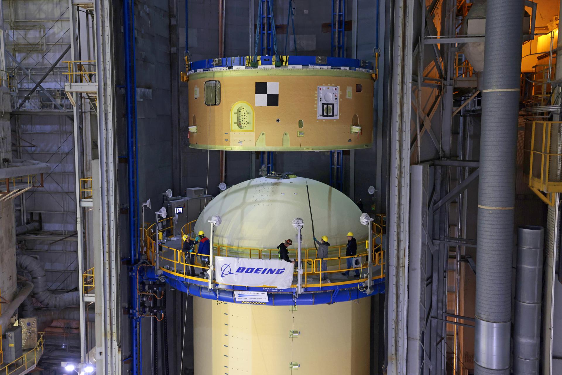 Move crews at NASA’s Michoud Assembly Facility in New Orleans lift the forward skirt for the agency’s SLS (Space Launch System) rocket core stage via an overhead crane system and sit it atop the previously mated intertank and liquid oxygen tank on Dec. 5, 2025. Teams with Boeing – NASA’s Prime Contractor for SLS – will mate the forward skirt to the forward end of the liquid oxygen tank to complete forward join operations for the core stage of the agency’s Artemis III mission. The forward skirt houses flight computers, cameras and avionics systems, and is one of five major elements that make up the 212-foot-tall rocket stage. The core stage, along with its four RS-25 engines, produce more than two million pounds of thrust to help launch NASA’s Orion spacecraft, astronauts, and supplies beyond Earth’s orbit and to the lunar surface for Artemis. Image credit: NASA/Michael DeMocker