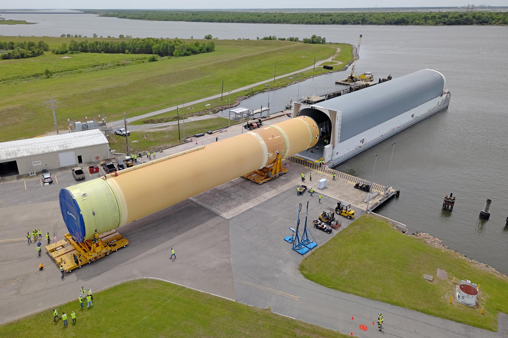 NASA moved the core stage, or the largest section, of the SLS (Space Launch System) rocket that will launch the crewed Artemis III mission in 2027 from the agency’s Michoud Assembly Facility to the agency’s Pegasus barge in New Orleans on April 20. The barge will ferry the top four-fifths – the section containing the liquid hydrogen tank, liquid oxygen tank, intertank, and forward skirt – of the SLS core stage to NASA’s Kennedy Space Center in Florida to complete outfitting and vertical integration. Teams with NASA and Boeing, the SLS core stage lead contractor, used specialized transporters to guide the top four-fifths from the NASA rocket factory to Pegasus. Prior to the move, technicians added an engine section transportation simulator to the rocket stage for shipment to the Space Coast. Next year’s Artemis III mission will launch astronauts to Earth’s orbit aboard the Orion spacecraft on top of SLS to test rendezvous and docking capabilities between Orion and commercial spacecraft needed to land Artemis IV astronauts on the Moon in 2028. NASA’s SLS is the only rocket capable of sending Orion, astronauts, and supplies to the Moon in a single launch.