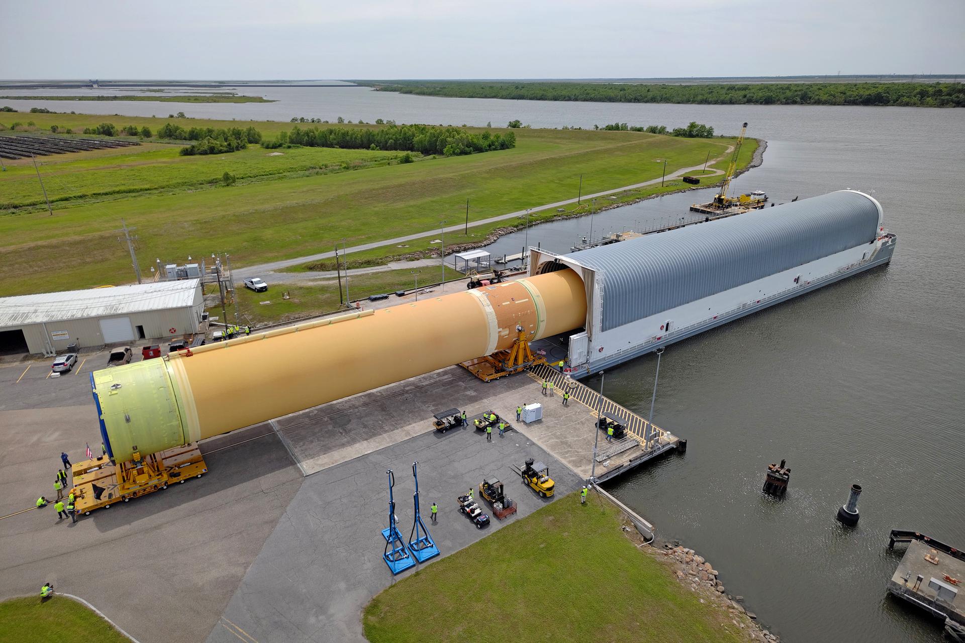 NASA moved the core stage, or the largest section, of the SLS (Space Launch System) rocket that will launch the crewed Artemis III mission in 2027 from the agency’s Michoud Assembly Facility to the agency’s Pegasus barge in New Orleans on April 20. The barge will ferry the top four-fifths – the section containing the liquid hydrogen tank, liquid oxygen tank, intertank, and forward skirt – of the SLS core stage to NASA’s Kennedy Space Center in Florida to complete outfitting and vertical integration.  Teams with NASA and Boeing, the SLS core stage lead contractor, used specialized transporters to guide the top four-fifths from the NASA rocket factory to Pegasus. Prior to the move, technicians added an engine section transportation simulator to the rocket stage for shipment to the Space Coast.  Next year’s Artemis III mission will launch astronauts to Earth’s orbit aboard the Orion spacecraft on top of SLS to test rendezvous and docking capabilities between Orion and commercial spacecraft needed to land Artemis IV astronauts on the Moon in 2028. NASA’s SLS is the only rocket capable of sending Orion, astronauts, and supplies to the Moon in a single launch.  Image credit: NASA/Michael DeMocker