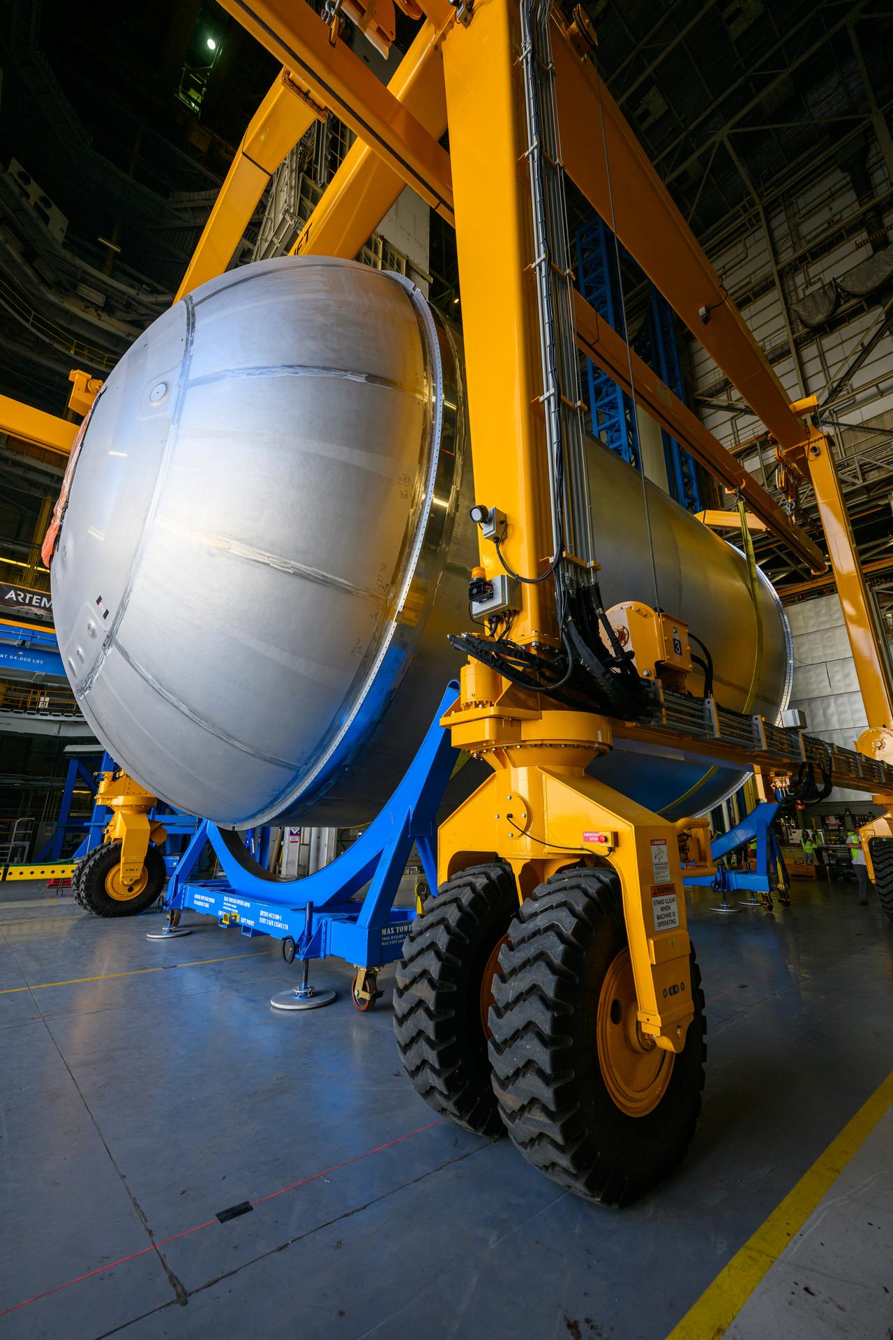 Teams at NASA’s Michoud Assembly Facility in New Orleans use a heavy-lift mobile transport apparatus to move a 51-foot-tall liquid oxygen tank out of the vertical assembly building and into the main rocket factory on June 11. The liquidoxygen tank will form part of the SLS (Space Launch System) rocket for NASA’s Artemis IV mission to the Moon. Next, technicians with Boeing, SLS core stage prime contractor, and NASA will perform dimensional inspections and install internal baffles on the propellant tank before the next phase of production. The propellant tank will hold more than 196,000 gallons of super-cooled liquid oxygen at launch and is one of five major elements that make up the 212-foot-tall SLS rocket stage. The core stage, along with its four RS-25 engines at its base, produces more than two million pounds of thrust to help launch NASA’s Orion spacecraft, ronauts, and supplies beyond Earth’s orbit and to the lunar surface for Artemis.