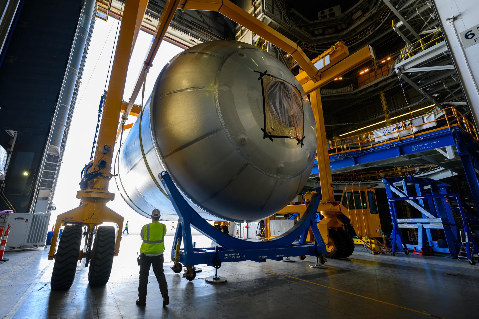 Teams at NASA’s Michoud Assembly Facility in New Orleans use a heavy-lift mobile transport apparatus to move a 51-foot-tall liquid oxygen tank out of the vertical assembly building and into the main rocket factory on June 11. The liquidoxygen tank will form part of the SLS (Space Launch System) rocket for NASA’s Artemis IV mission to the Moon. Next, technicians with Boeing, SLS core stage prime contractor, and NASA will perform dimensional inspections and install internal baffles on the propellant tank before the next phase of production. The propellant tank will hold more than 196,000 gallons of super-cooled liquid oxygen at launch and is one of five major elements that make up the 212-foot-tall SLS rocket stage. The core stage, along with its four RS-25 engines at its base, produces more than two million pounds of thrust to help launch NASA’s Orion spacecraft, ronauts, and supplies beyond Earth’s orbit and to the lunar surface for Artemis.
