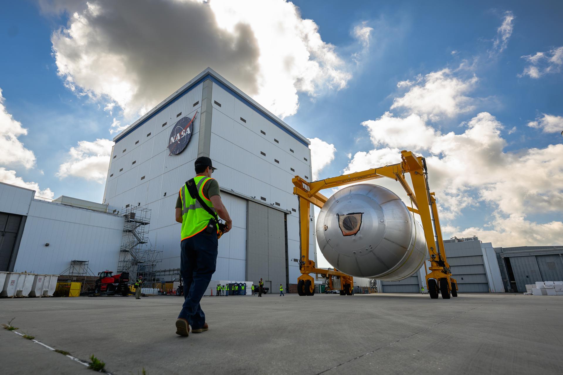 Teams at NASA’s Michoud Assembly Facility in New Orleans use a heavy-lift mobile transport apparatus to move a 51-foot-tall liquid oxygen tank out of the vertical assembly building and into the main rocket factory on June 11. The liquidoxygen tank will form part of the SLS (Space Launch System) rocket for NASA’s Artemis IV mission to the Moon. Next, technicians with Boeing, SLS core stage prime contractor, and NASA will perform dimensional inspections and install internal baffles on the propellant tank before the next phase of production. The propellant tank will hold more than 196,000 gallons of super-cooled liquid oxygen at launch and is one of five major elements that make up the 212-foot-tall SLS rocket stage. The core stage, along with its four RS-25 engines at its base, produces more than two million pounds of thrust to help launch NASA’s Orion spacecraft, ronauts, and supplies beyond Earth’s orbit and to the lunar surface for Artemis.