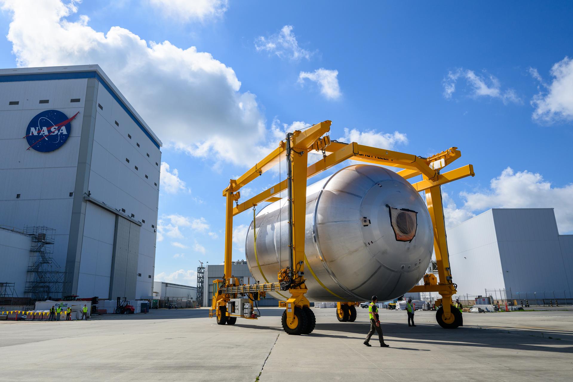 Teams at NASA’s Michoud Assembly Facility in New Orleans use a heavy-lift mobile transport apparatus to move a 51-foot-tall liquid oxygen tank out of the vertical assembly building and into the main rocket factory on June 11. The liquidoxygen tank will form part of the SLS (Space Launch System) rocket for NASA’s Artemis IV mission to the Moon. Next, technicians with Boeing, SLS core stage prime contractor, and NASA will perform dimensional inspections and install internal baffles on the propellant tank before the next phase of production. The propellant tank will hold more than 196,000 gallons of super-cooled liquid oxygen at launch and is one of five major elements that make up the 212-foot-tall SLS rocket stage. The core stage, along with its four RS-25 engines at its base, produces more than two million pounds of thrust to help launch NASA’s Orion spacecraft, ronauts, and supplies beyond Earth’s orbit and to the lunar surface for Artemis.