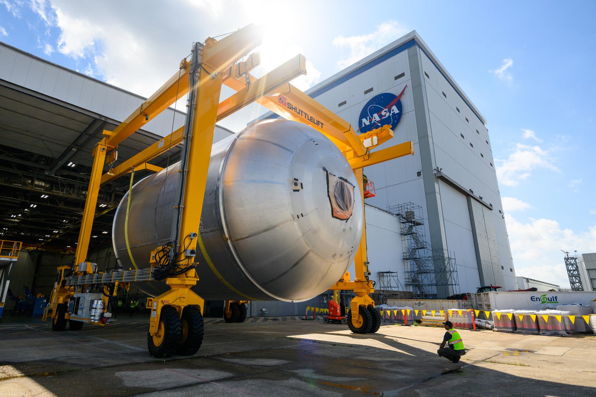 Teams at NASA’s Michoud Assembly Facility in New Orleans use a heavy-lift mobile transport apparatus to move a 51-foot-tall liquid oxygen tank out of the vertical assembly building and into the main rocket factory on June 11. The liquidoxygen tank will form part of the SLS (Space Launch System) rocket for NASA’s Artemis IV mission to the Moon. Next, technicians with Boeing, SLS core stage prime contractor, and NASA will perform dimensional inspections and install internal baffles on the propellant tank before the next phase of production. The propellant tank will hold more than 196,000 gallons of super-cooled liquid oxygen at launch and is one of five major elements that make up the 212-foot-tall SLS rocket stage. The core stage, along with its four RS-25 engines at its base, produces more than two million pounds of thrust to help launch NASA’s Orion spacecraft, ronauts, and supplies beyond Earth’s orbit and to the lunar surface for Artemis.