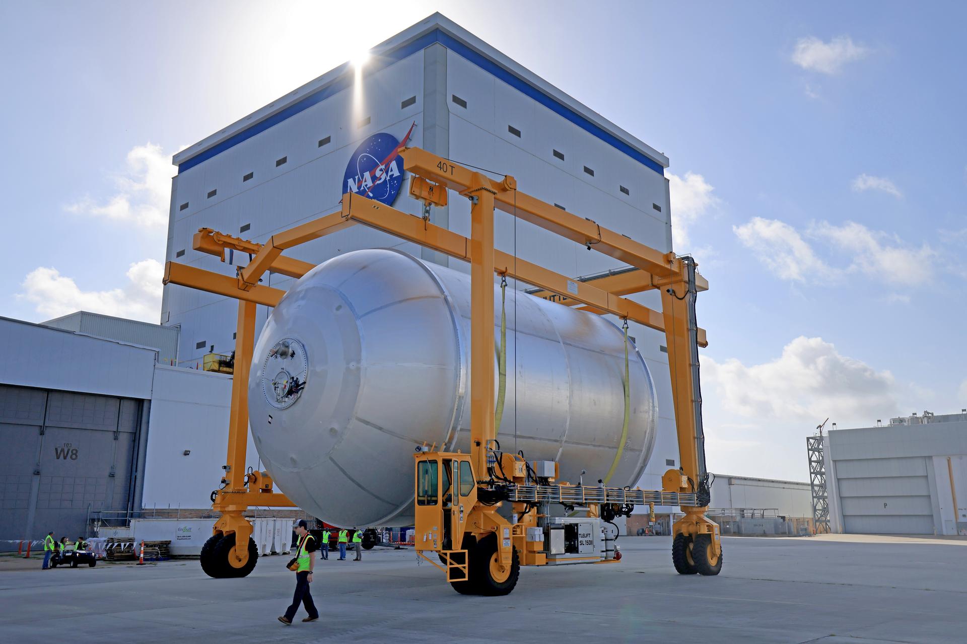 Teams at NASA’s Michoud Assembly Facility in New Orleans transport a 51-foot-tall liquid oxygen tank out of the vertical assembly building on July 23, 2026. The liquid oxygen tank, which will form part of the SLS (Space Launch System) rocket for NASA’s Artemis IV mission to the Moon, is suspended in a strap carrier transport apparatus and brought into the main factory building. Here, teams with SLS core stage prime contractor, Boeing, will perform post-proof non-destructive evaluations on the flight hardware before moving forward with tank cleaning. The propellant tank will hold more than 196,000 gallons of super-cooled liquid oxygen at launch and is one of five major elements that make up the 212-foot-tall SLS rocket stage. The core stage, along with its four RS-25 engines at its base, produces more than two million pounds of thrust to help launch NASA’s Orion spacecraft, astronauts, and supplies beyond Earth’s orbit and to the lunar surface for Artemis.  Image credit: NASA/Michael DeMocker