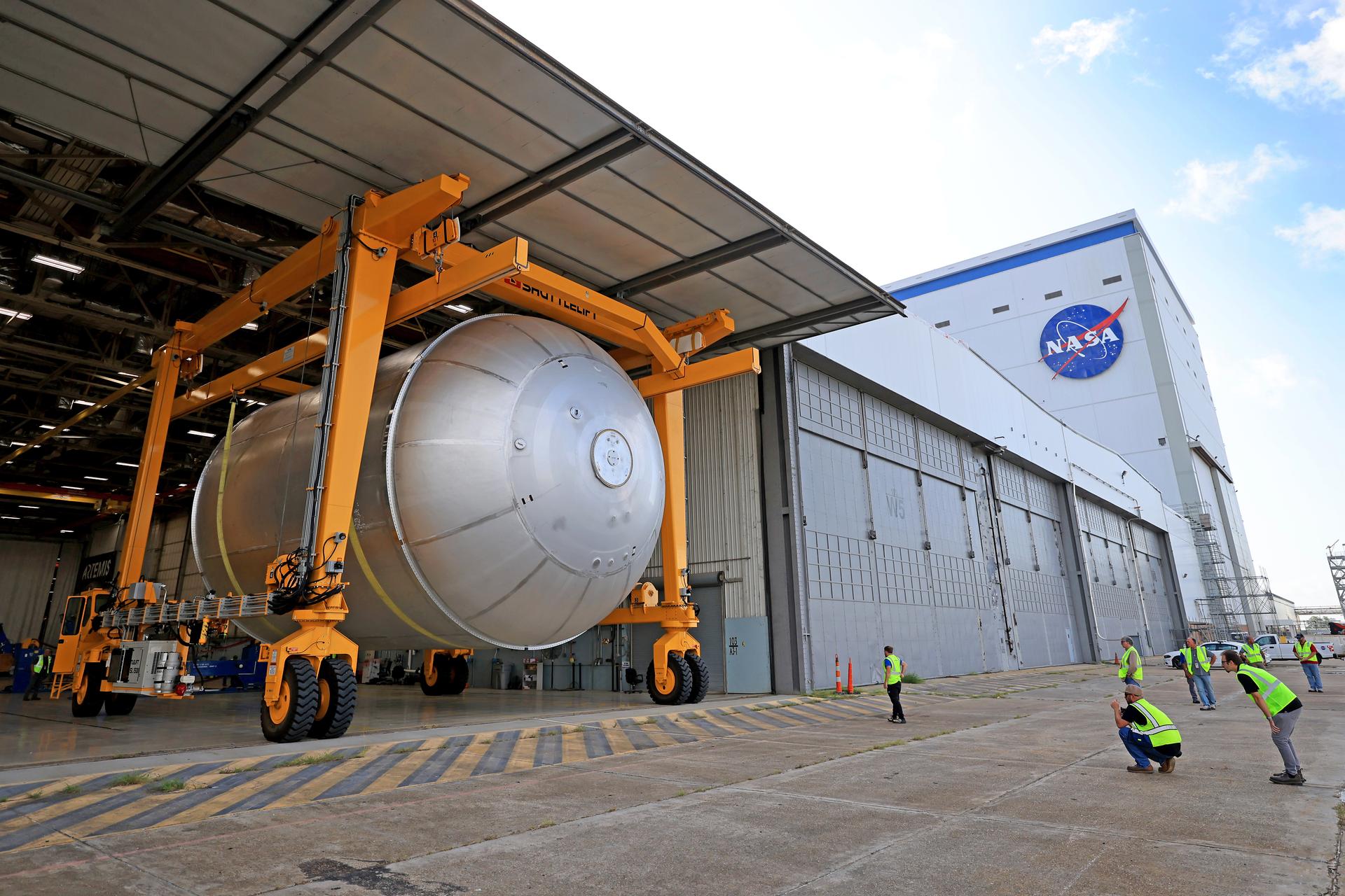 Teams at NASA’s Michoud Assembly Facility in New Orleans transport a 51-foot-tall liquid oxygen tank out of the vertical assembly building on July 23, 2026. The liquid oxygen tank, which will form part of the SLS (Space Launch System) rocket for NASA’s Artemis IV mission to the Moon, is suspended in a strap carrier transport apparatus and brought into the main factory building. Here, teams with SLS core stage prime contractor, Boeing, will perform post-proof non-destructive evaluations on the flight hardware before moving forward with tank cleaning. The propellant tank will hold more than 196,000 gallons of super-cooled liquid oxygen at launch and is one of five major elements that make up the 212-foot-tall SLS rocket stage. The core stage, along with its four RS-25 engines at its base, produces more than two million pounds of thrust to help launch NASA’s Orion spacecraft, astronauts, and supplies beyond Earth’s orbit and to the lunar surface for Artemis.  Image credit: NASA/Michael DeMocker
