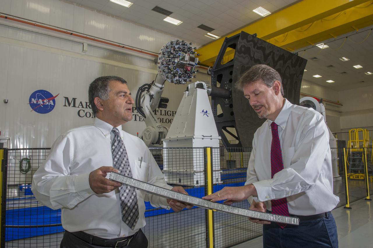 MAJID BABAI, LEFT, CHIEF OF THE NONMETALLIC MANUFACTURING BRANCH AT MARSHALL, AND STEPHEN RICHARDSON, LEAD FOR THE STRUCTURAL DEVELOPMENT TEAM, TAKE A CLOSER LOOK AT ONE OF THE FIRST TEST BUILDS MADE BY THE NEW ROBOTIC FIBER PLACEMENT MACHINE BEHIND THEM.