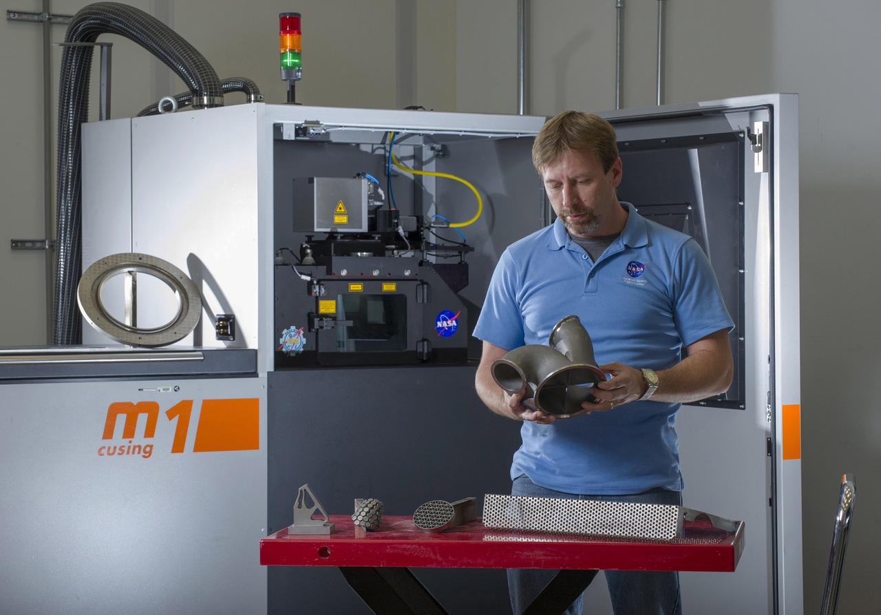 KEN COOPER, TEAM LEAD OF MSFC’S ADVANCED MANUFACTURING TEAM, WITH NICKEL ALLOY 718 PARTS FABRICATED USING THE M1 SELECTIVE LASER MELTING SYSTEM. THE M1 MACHINE IS DEDICATED TO BUILDING QUALIFICATION SAMPLES AND HARDWARE DEMONSTRATORS FOR THE RS25 ENGINE PROJECT.