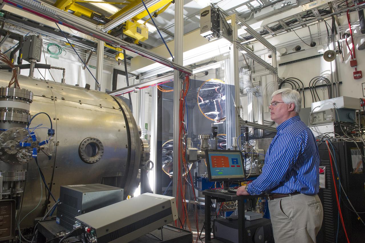 TODD SCHNEIDER ADJUSTS THE LIGHT HITTING A SAMPLE INSIDE THE HIGH INTENSITY SOLAR ENVIRONMENT TEST SYSTEM CHAMBER.